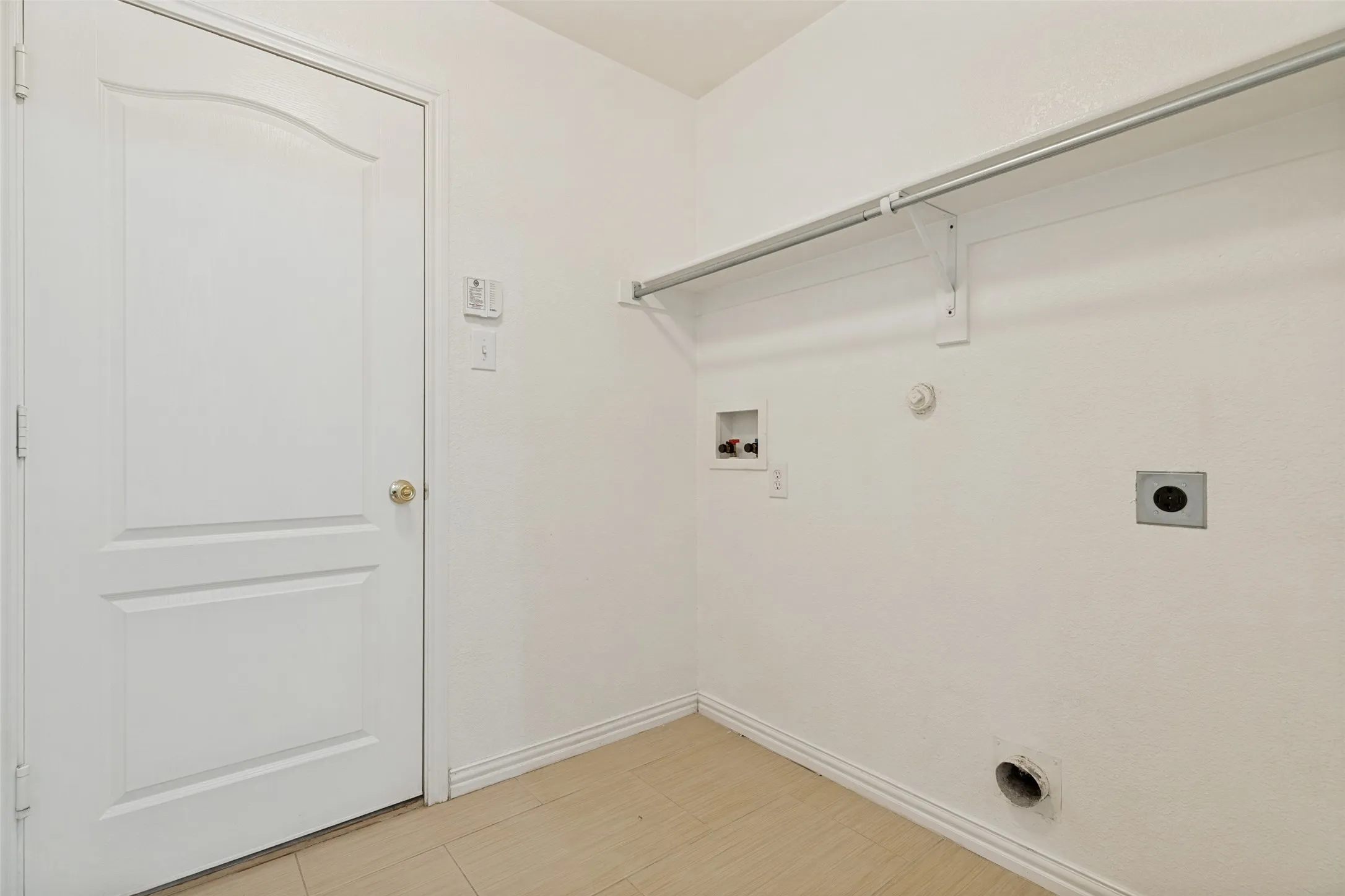 Laundry area with wood-finish flooring, built-in hanging rod, and utilities hookups