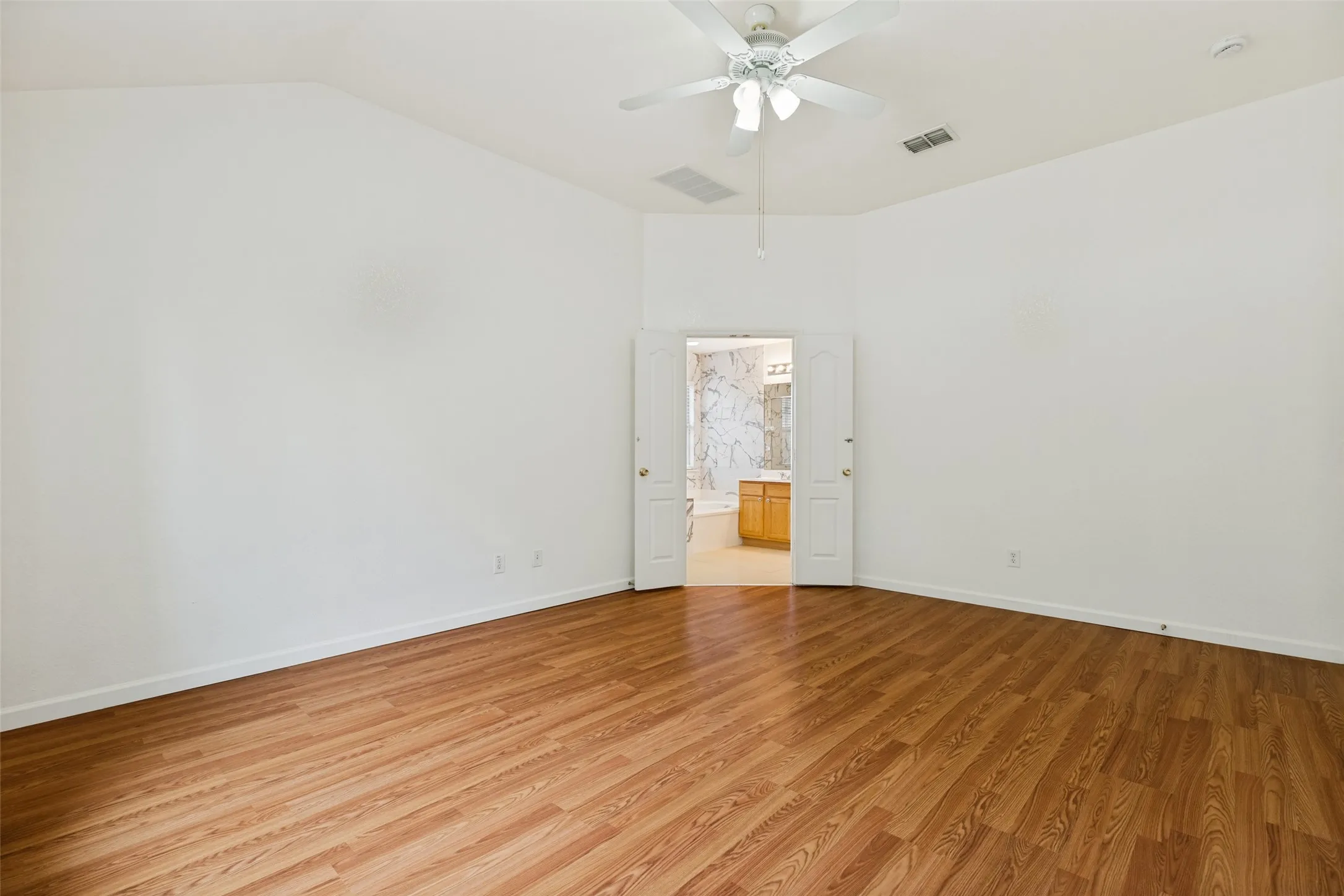 Vaulted ceiling with a ceiling fan, wood-finish flooring, and double-door entry