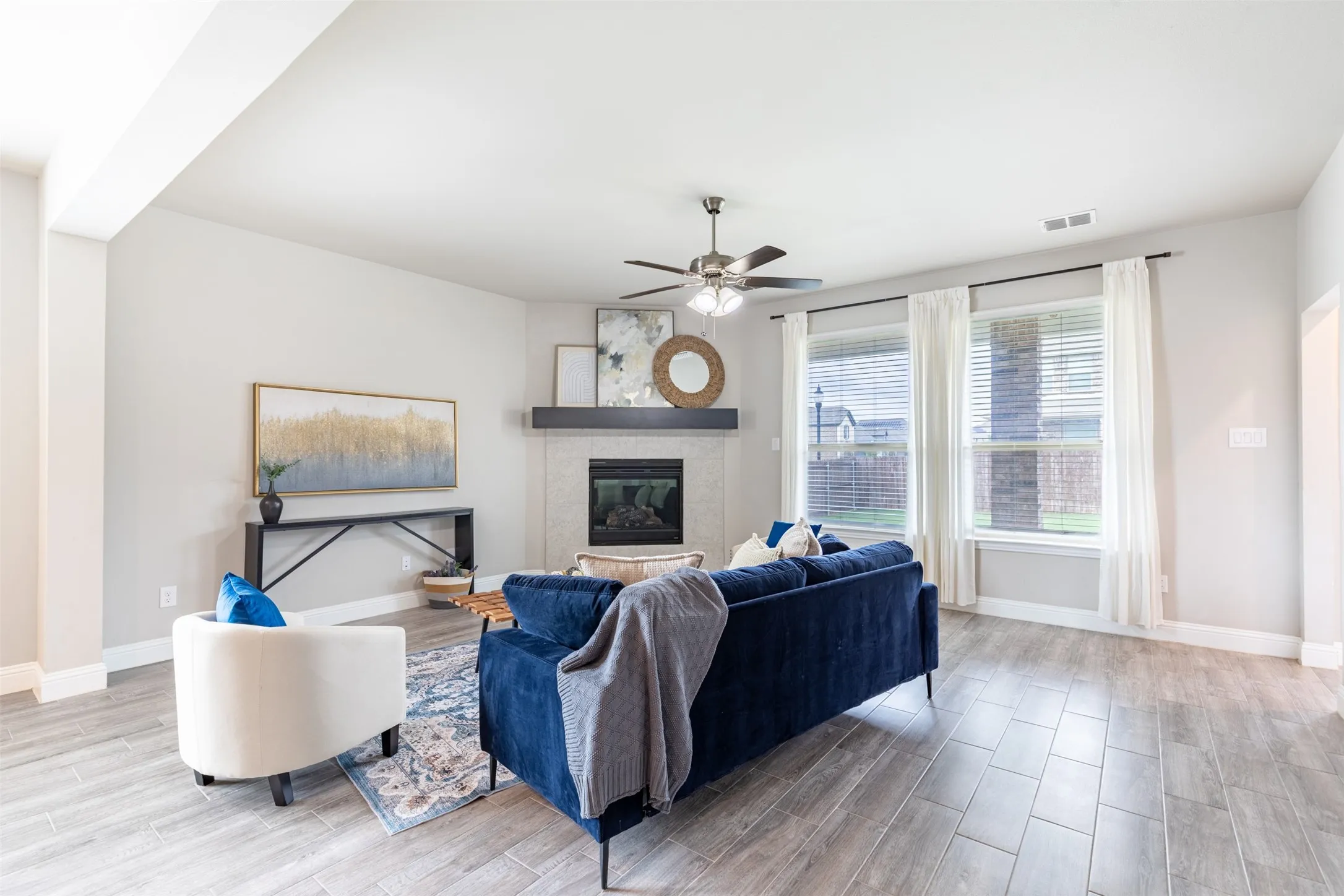 Spacious living room with a gas fireplace and log insert, cable TV hookup, and large windows overlooking the backyard with abundant natural light.