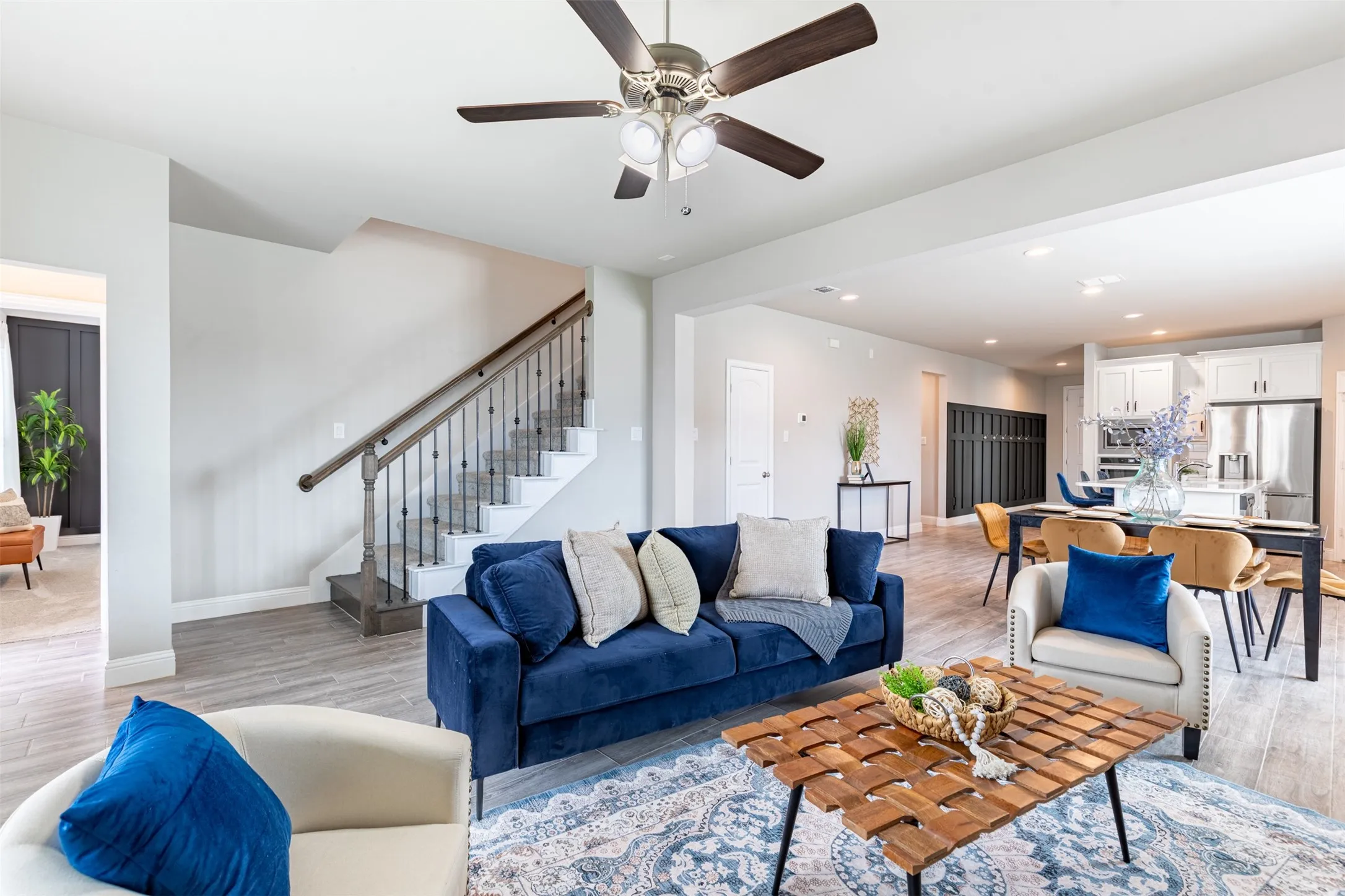 Spacious living room with upgraded iron stair railing, providing access to the second floor and a convenient hallway leading to the primary suite and backyard.