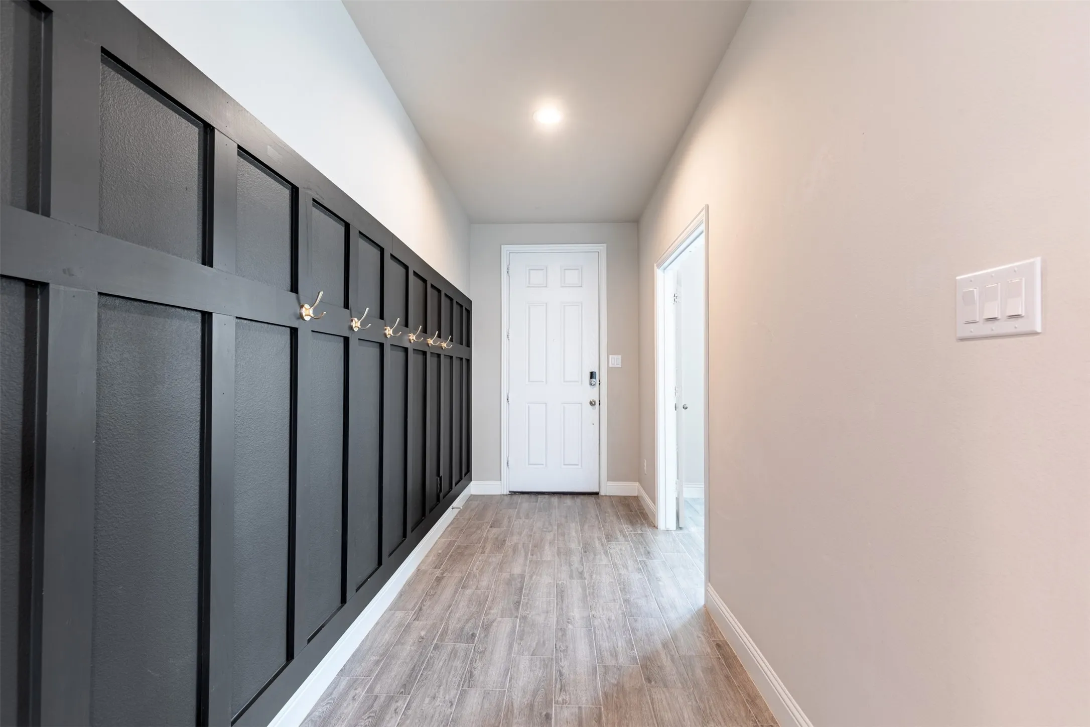 Welcoming entryway featuring a charming board-and-batten accent wall with convenient hooks, adding character and functional storage to the home.