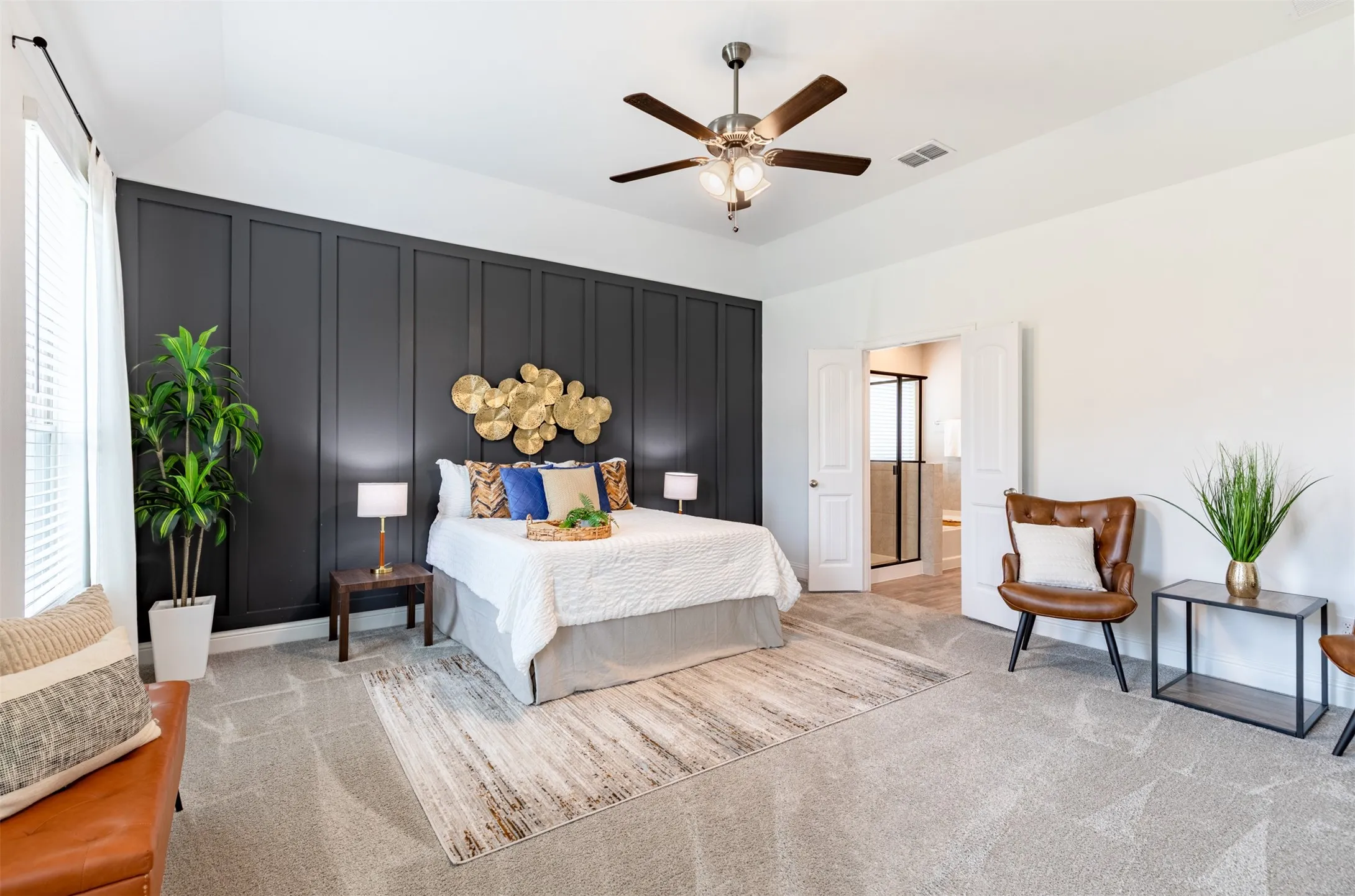 Spacious primary suite with large windows, abundant natural light, room for a king-size bed and sitting area, ceiling fan, and a stylish board-and-batten accent wall.