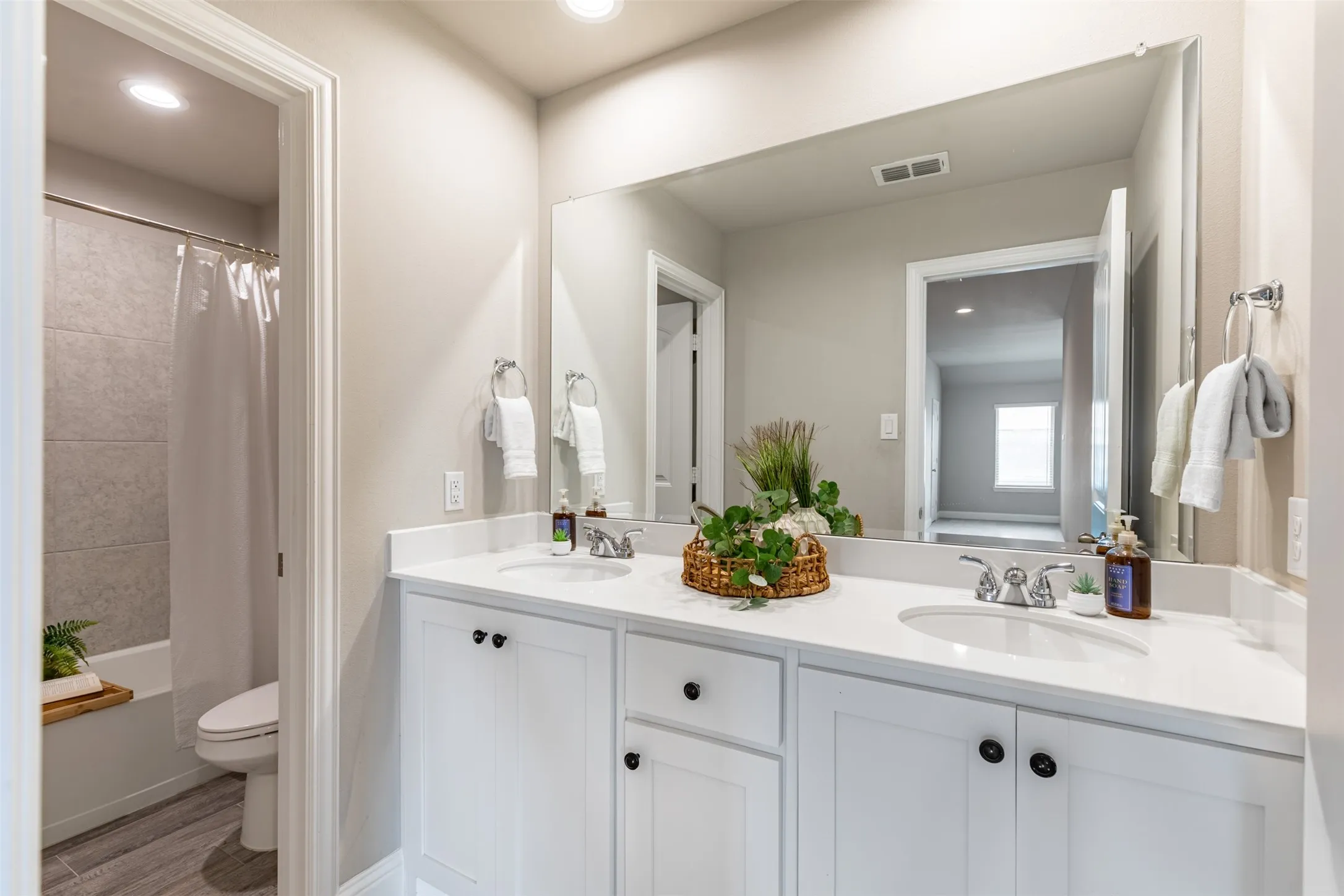Upstairs bathroom with a spacious double vanity and ample cabinetry, thoughtfully separated by a privacy door from the shower/tub combination and the double vanity area.