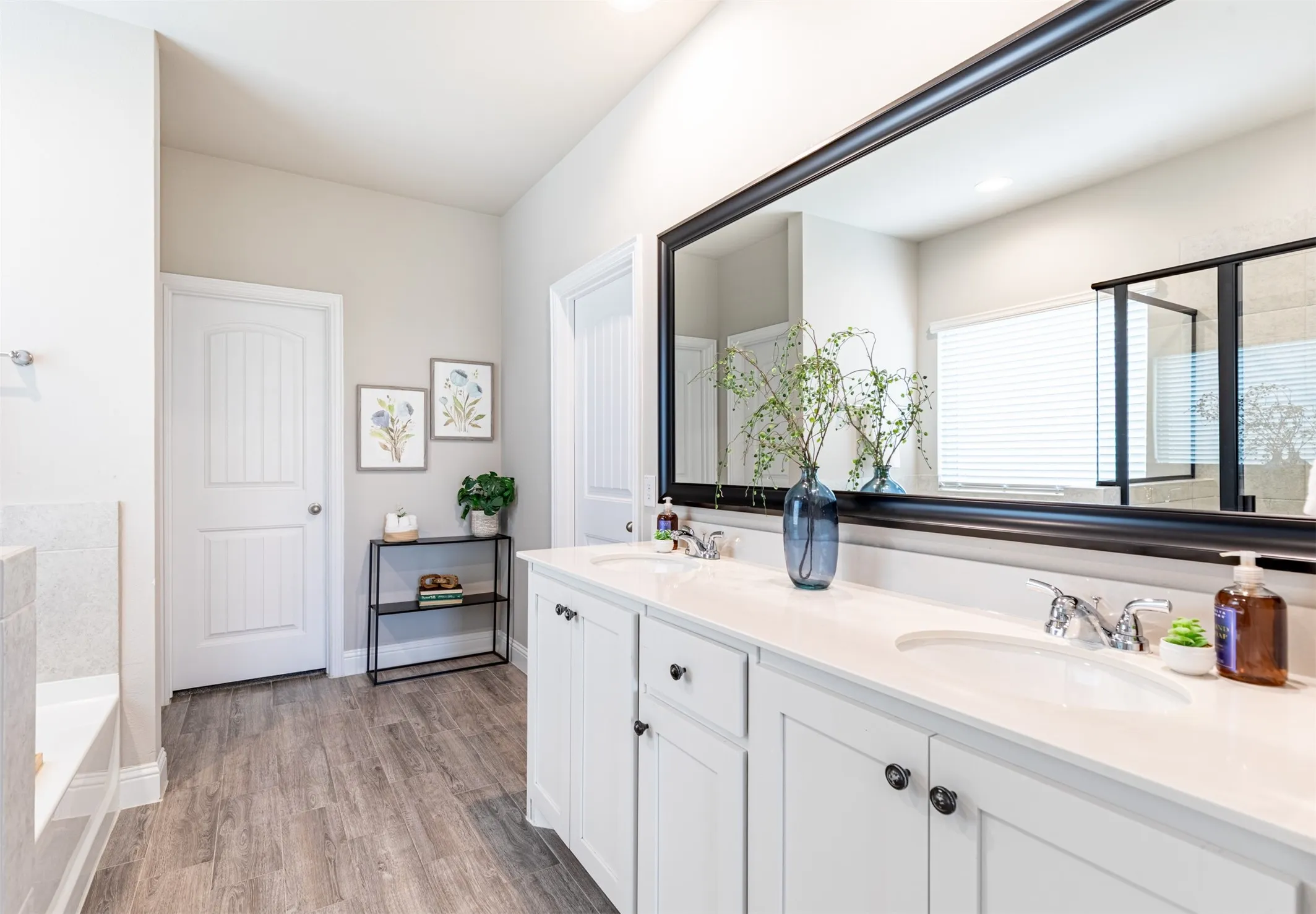 Primary bathroom featuring a spacious double vanity with ample storage and access to two oversized walk-in closets for exceptional storage and organization.