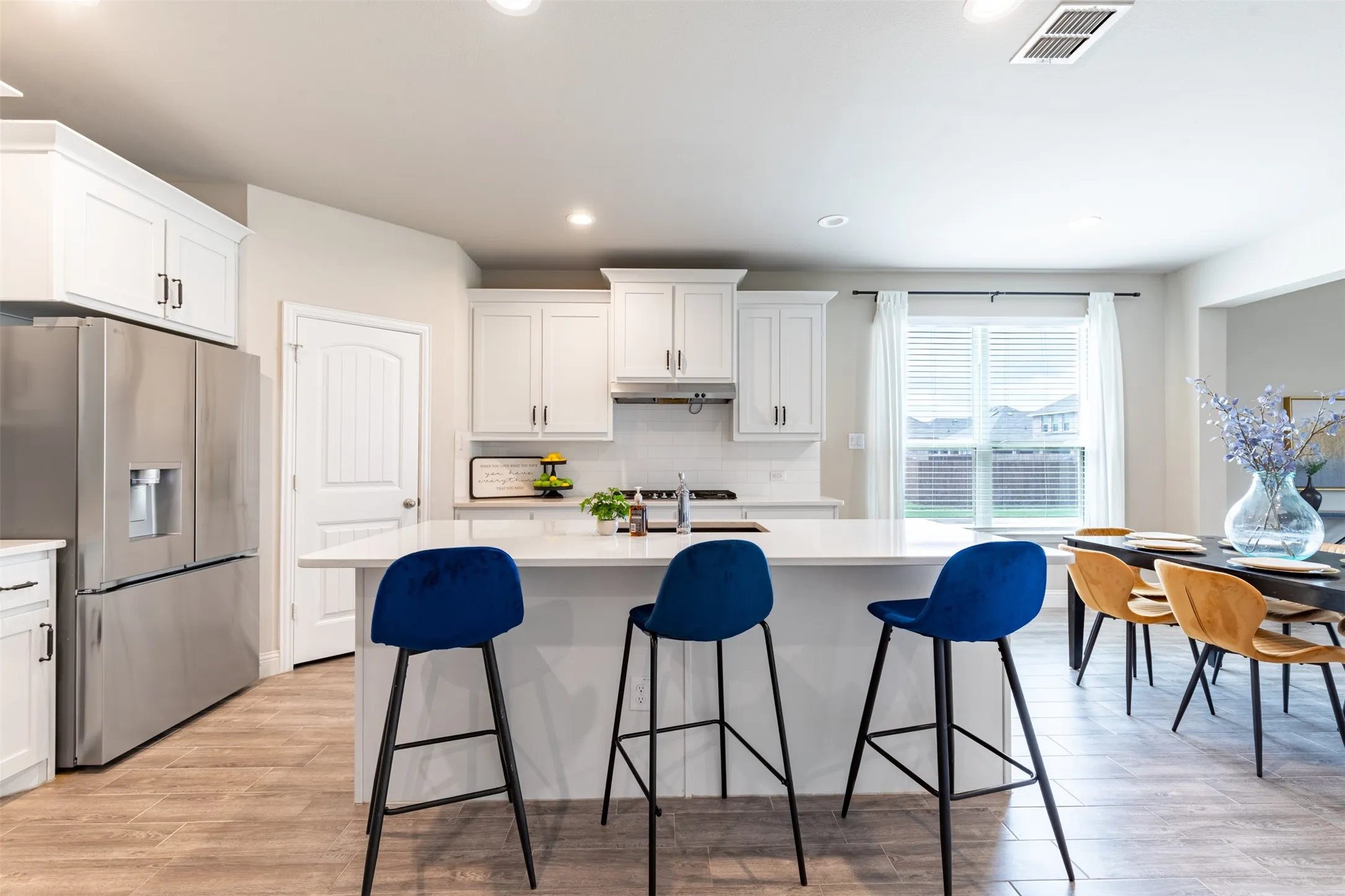 Spacious kitchen featuring a large island with bar seating, farmhouse sink and walk-in pantry, perfect for gathering and entertaining.