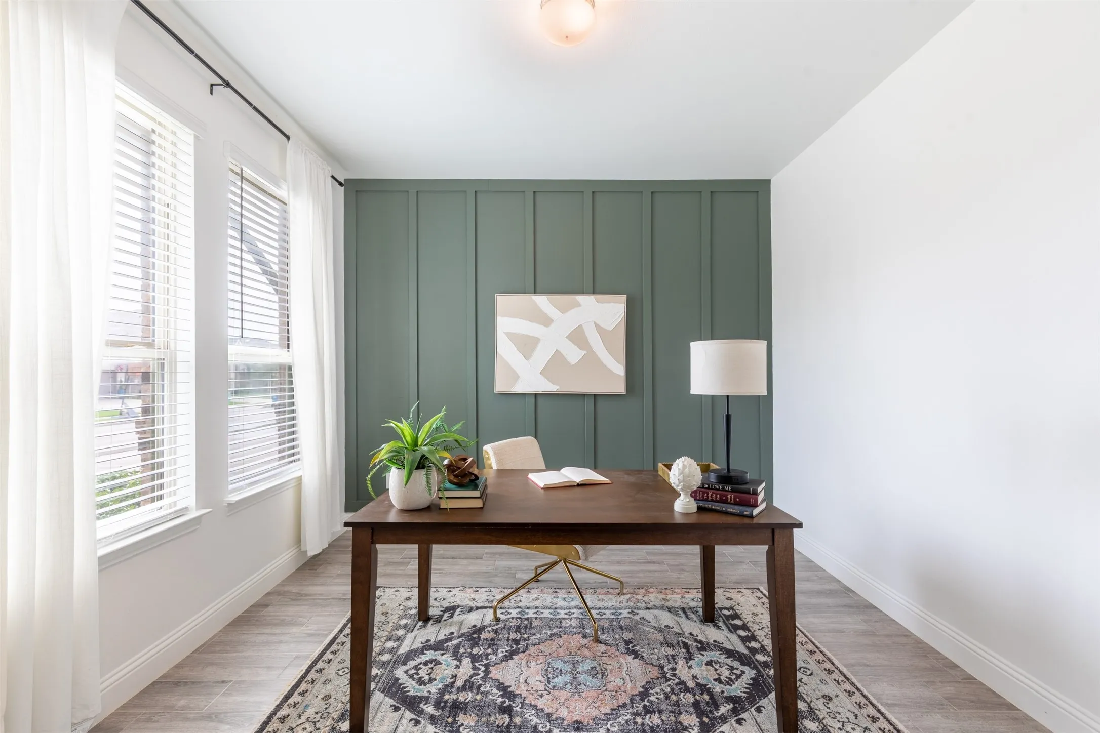 Spacious home office with large windows providing abundant natural light, complemented by a board-and-batten accent wall that adds character and timeless​​‌​​​​‌​​‌‌​‌‌​​​‌‌​‌​‌​‌​​​‌​​ style.