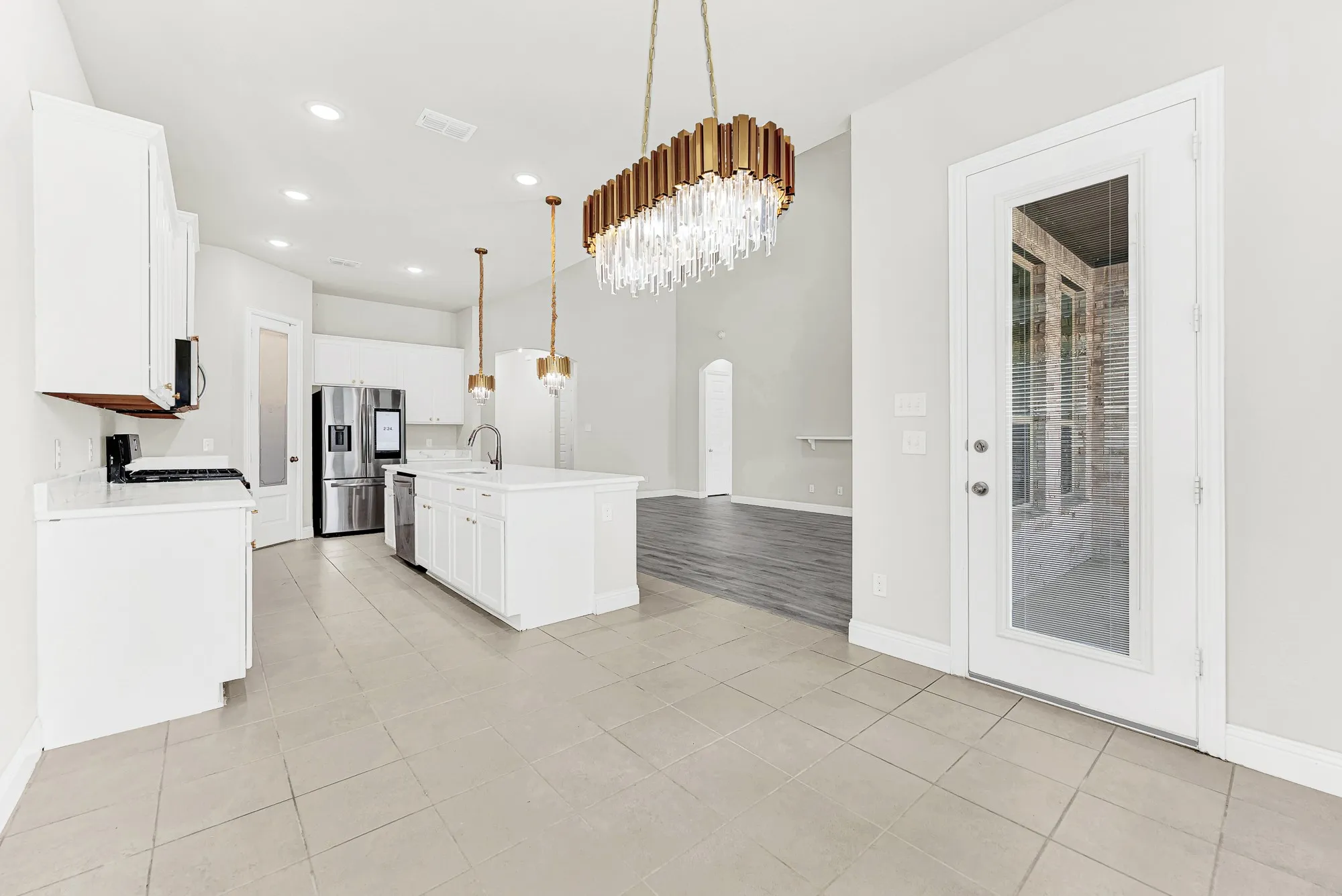 Glass patio doors link indoor tile flooring to outdoor breezes right beneath a statement dining chandelier. You can easily see yourself hosting weekend brunches that effortlessly flow outside on crisp sunny mornings.