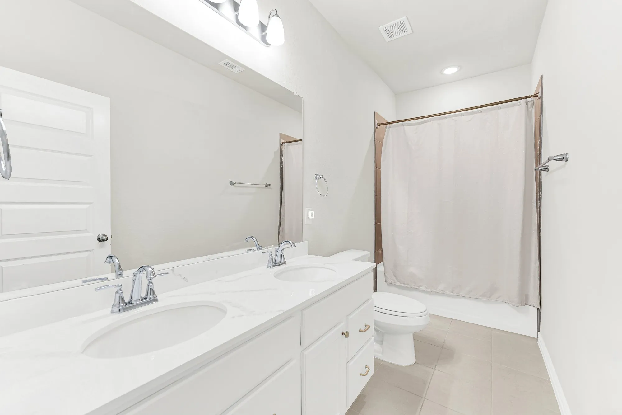 An expansive double-sink quartz vanity and large full-width mirror simplify busy morning routines. Imagine kids or guests getting ready for school or weekend outings simultaneously without ever feeling crowded.