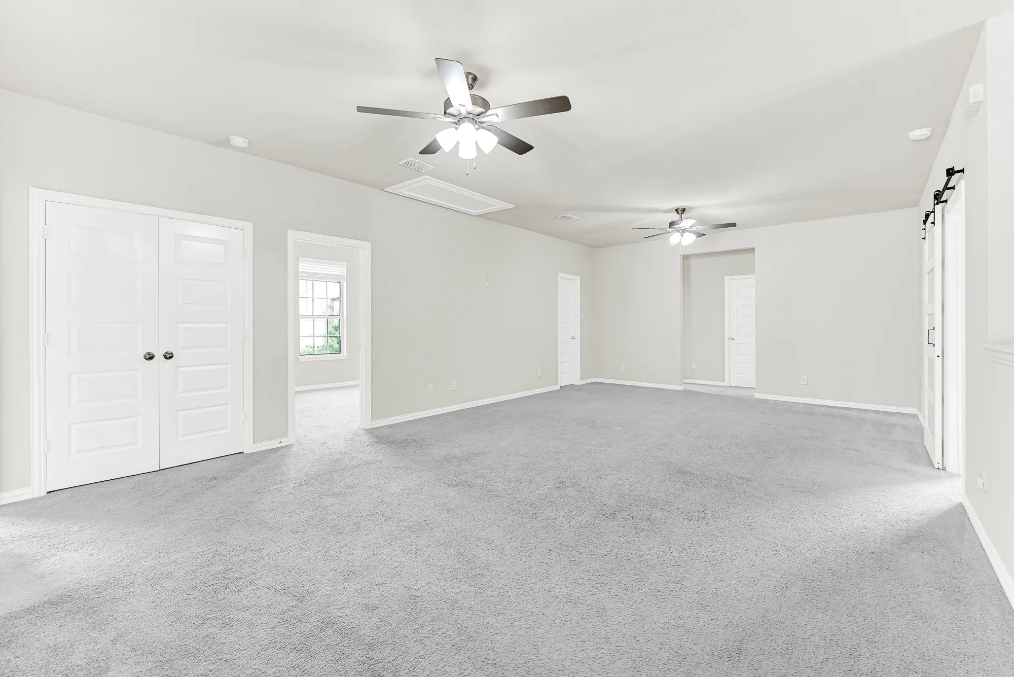 Double closet doors and multiple adjoining doorways frame an expansive footprint bathed in soft, balanced light. Envision hosting lively game nights with friends with plenty of open space to spread out comfortably