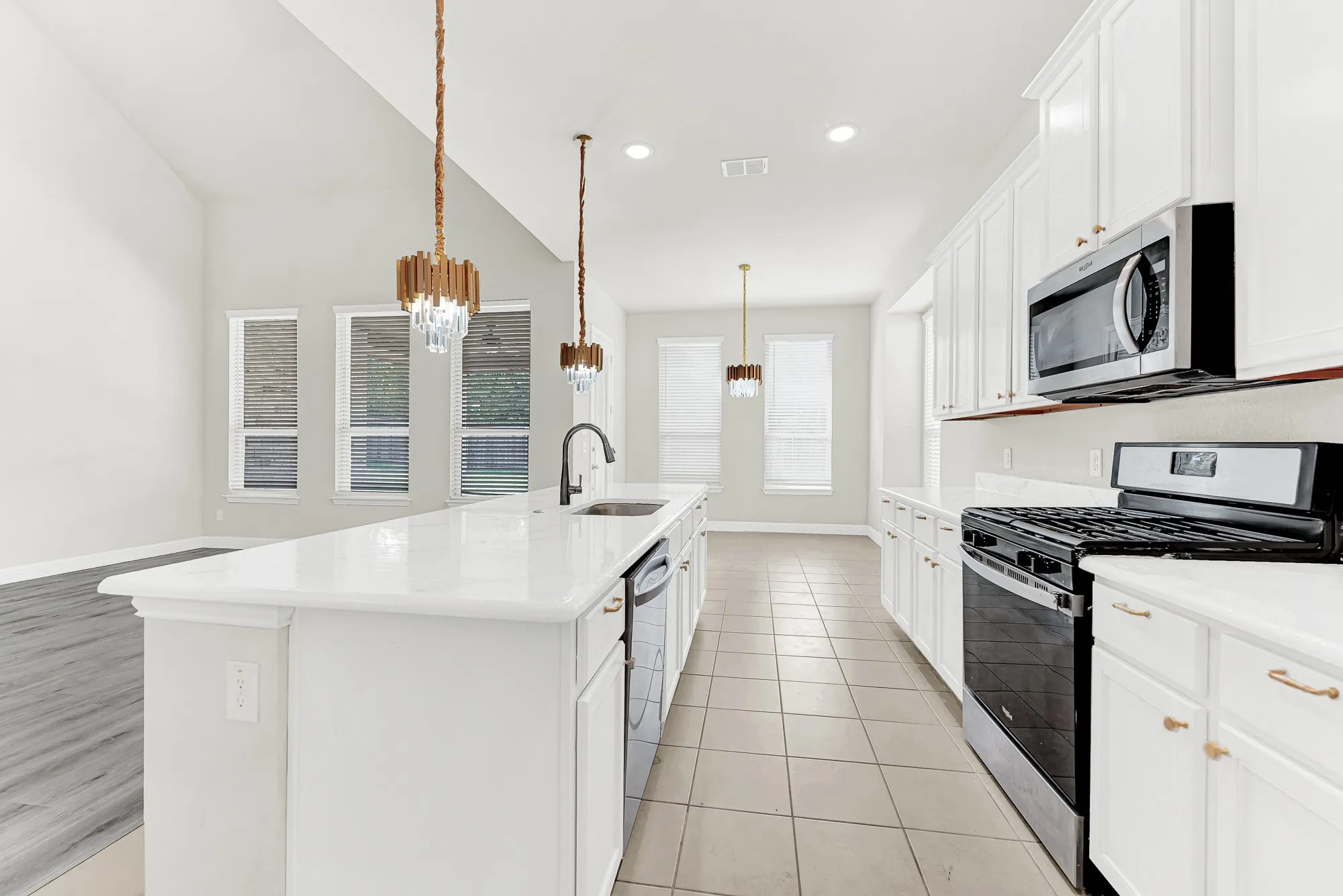 A sleek gas range anchors the main cooking line, looking past sparkling pendants into the sunlit breakfast corner. Imagine putting the finishing touches on a family feast while staying connected to every conversation nearby