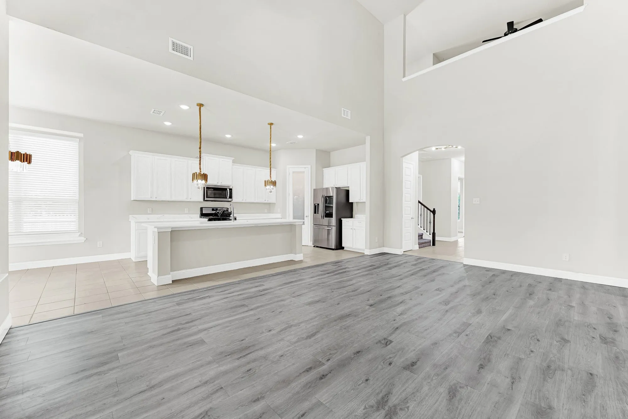 Soaring double-height ceilings bounce soft natural light across the seamless transition between living and culinary spaces. You can easily picture friends laughing together around the open layout while late-afternoon sun streams through the high alcoves.