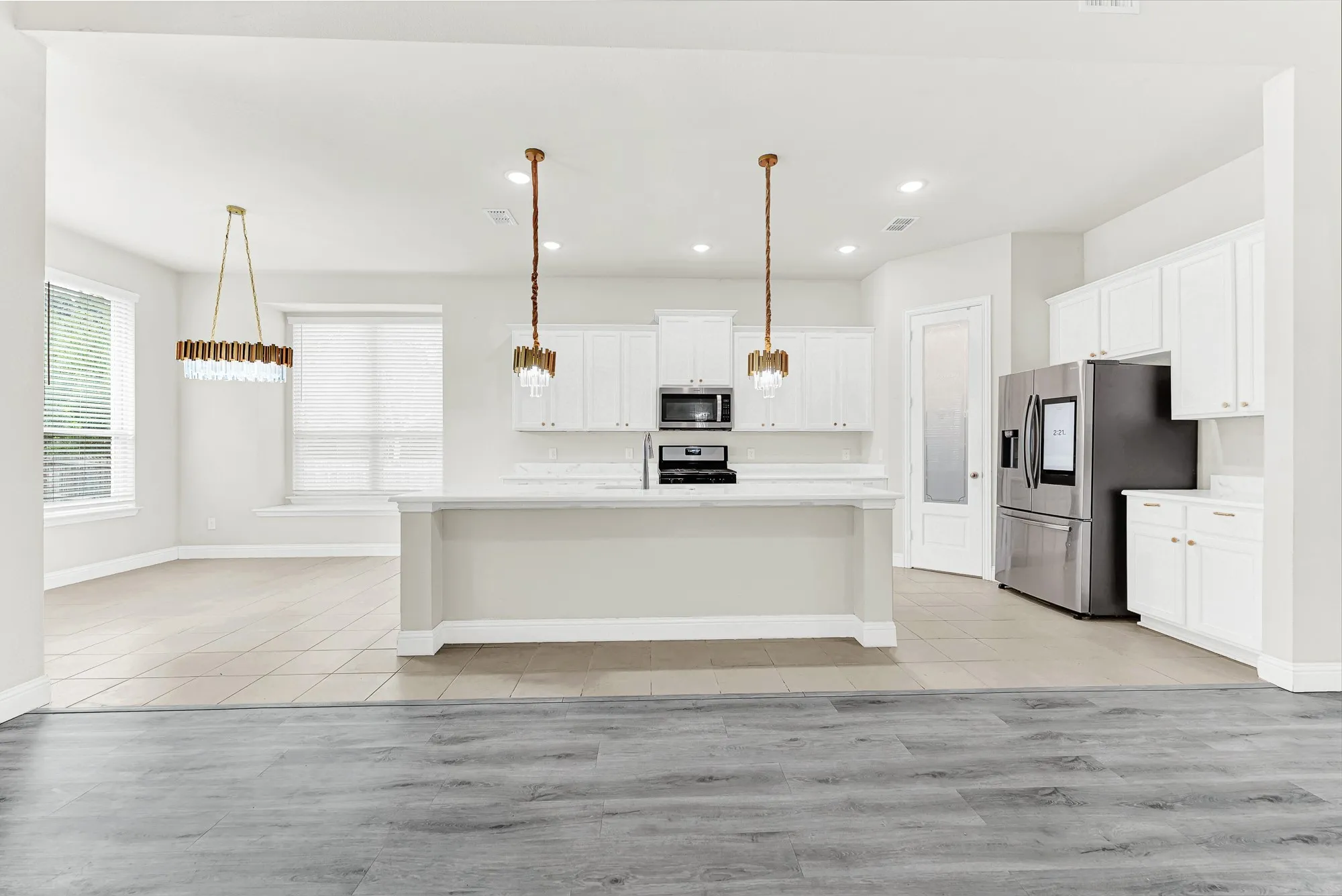 Symmetrical layout frames a wide central island under glowing pendant light ropes anchored by crisp white cabinetry. It’s easy to envision serving tapas and wine to guests gathered around the central island on a weekend evening.