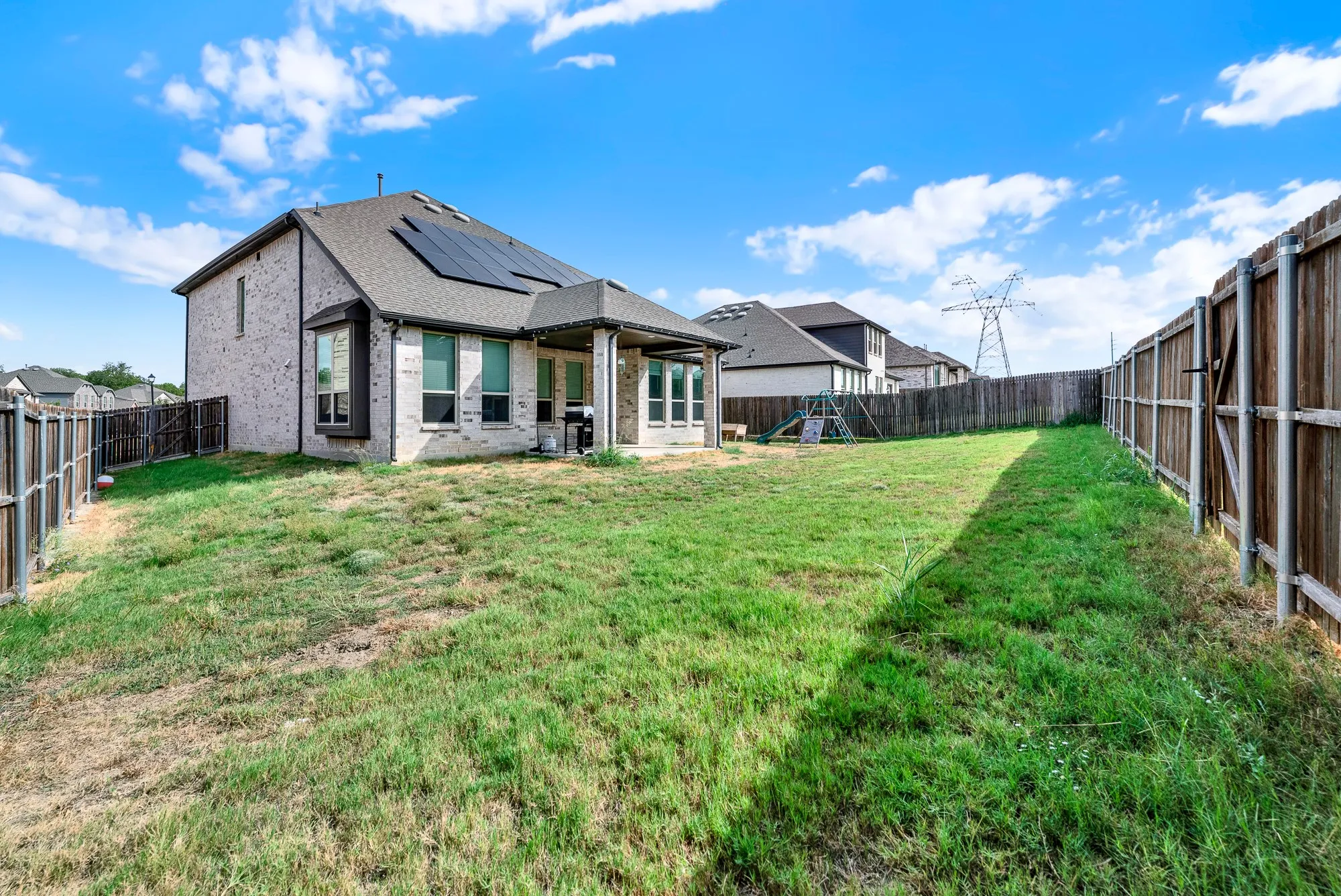 Generous side-yard depth and a protruding bay window detail frame the home's expansive perimeter footprint. Picture your dogs running freely across the secure, sprawling yard on sunny weekend afternoon