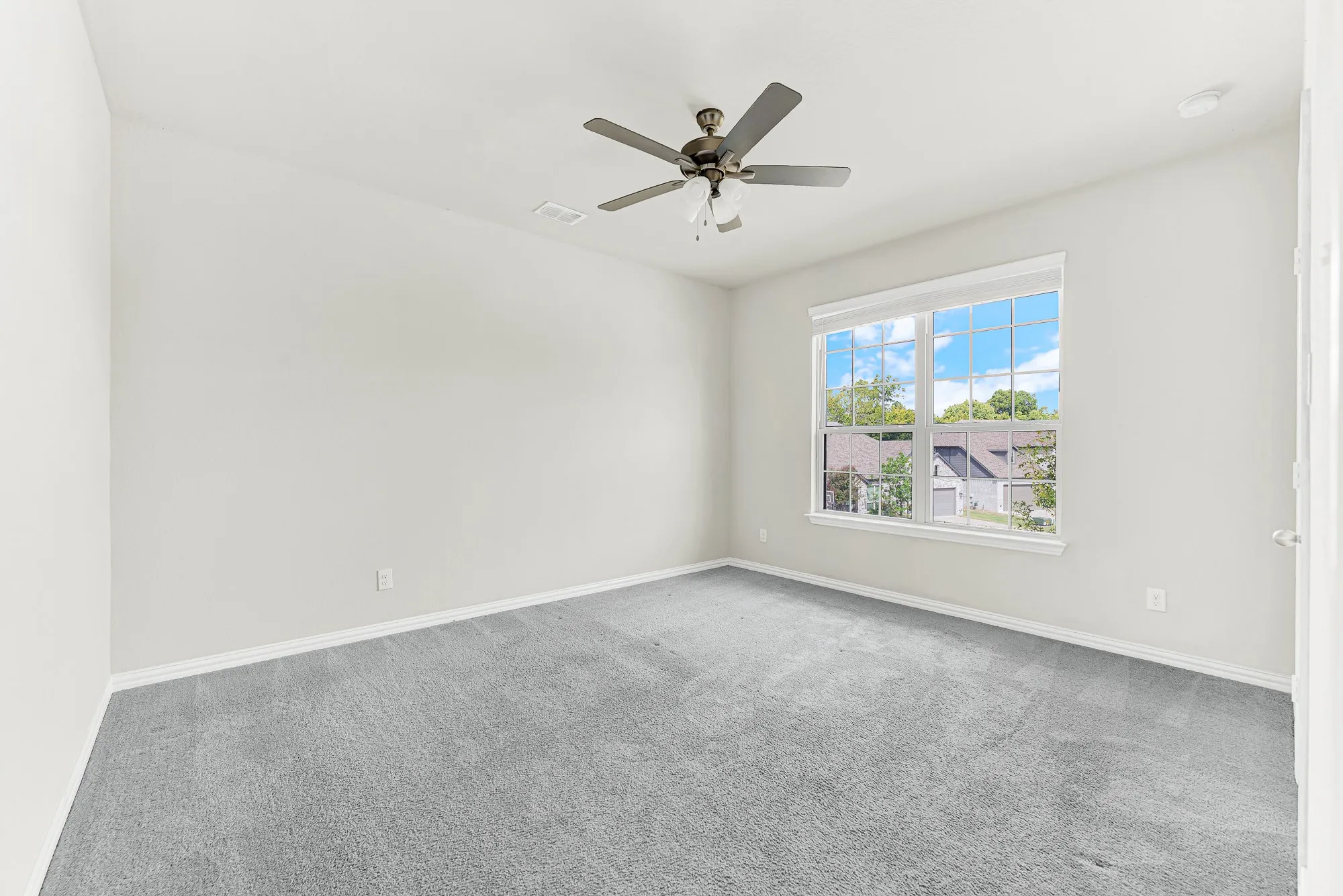 Broad multi-pane windows fill an open carpeted footprint with vibrant afternoon light. You can easily see yourself tailoring this versatile layout into a comfortable teenage bedroom or dedicated home gym.