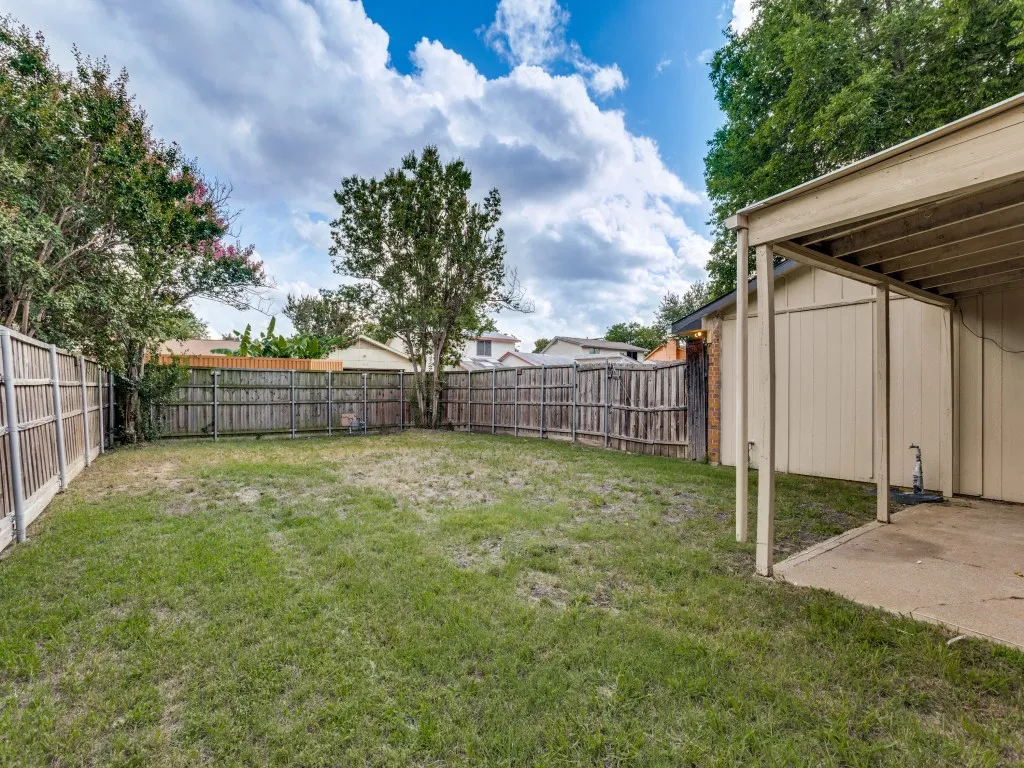 Expansive fenced backyard featuring a covered patio with a concrete surface