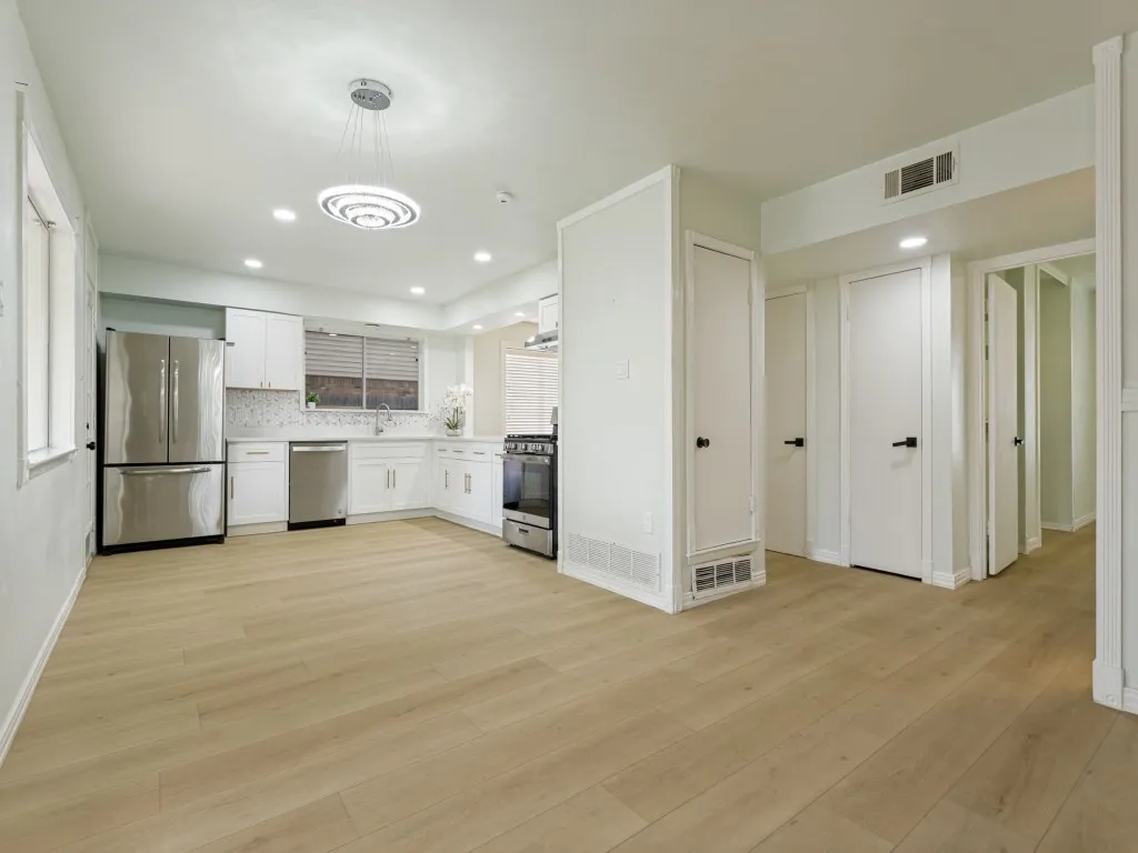 Open-concept kitchen featuring white cabinetry, stainless steel appliances, and a mosaic tile backsplash