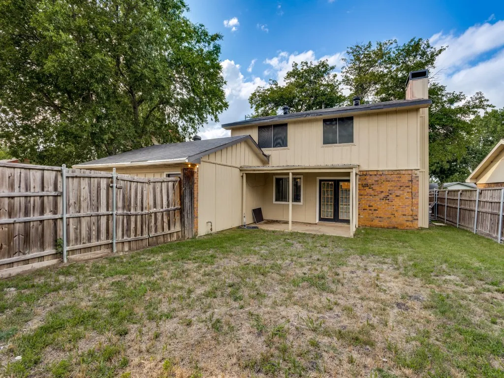 Rear exterior with a covered patio, brick and siding facade, and fenced yard