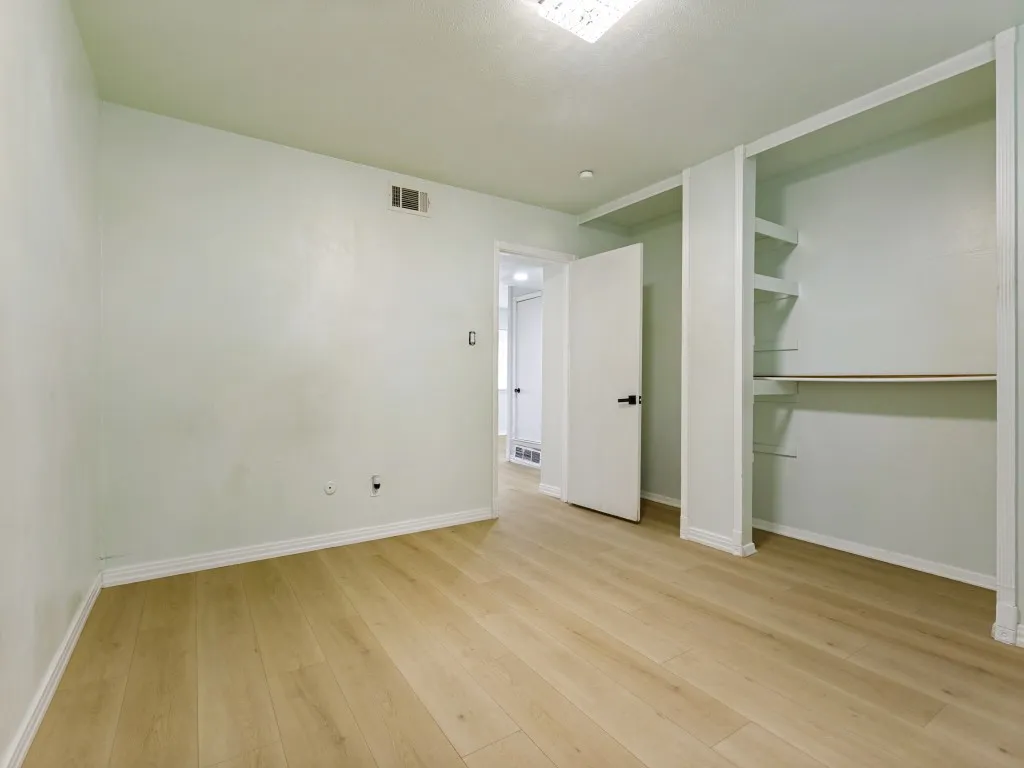 Wood-finish flooring, built-in shelving, white trim, and a ceiling-mounted light fixture