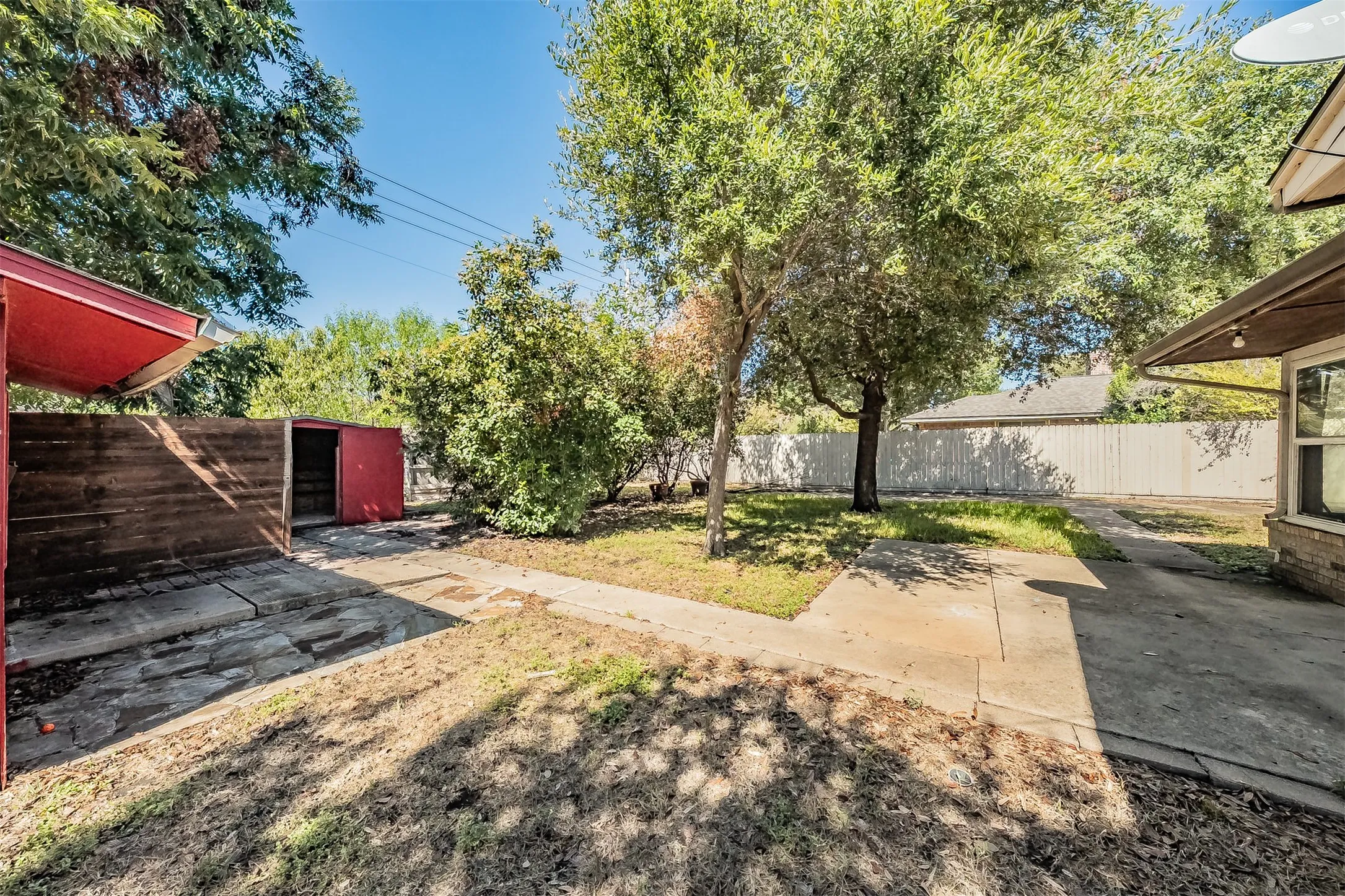 Expansive grassy yard area with mature trees and concrete pathways