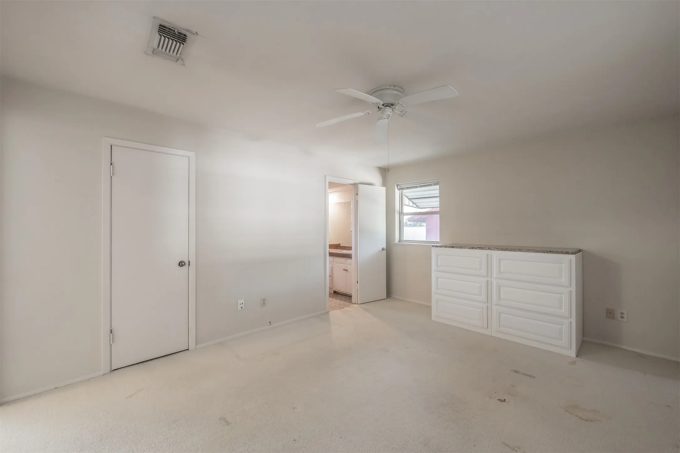 Spacious interior featuring a ceiling fan, a window, and a built-in dresser with a countertop