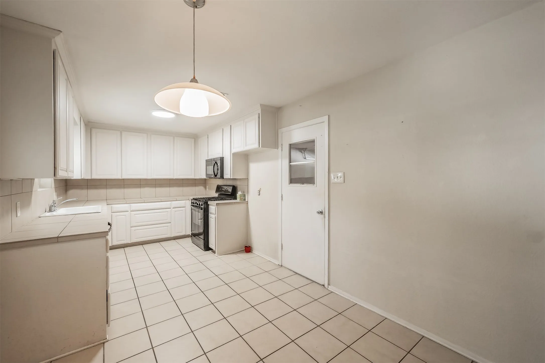 Kitchen featuring white cabinetry, tile flooring, and a tile backsplash
