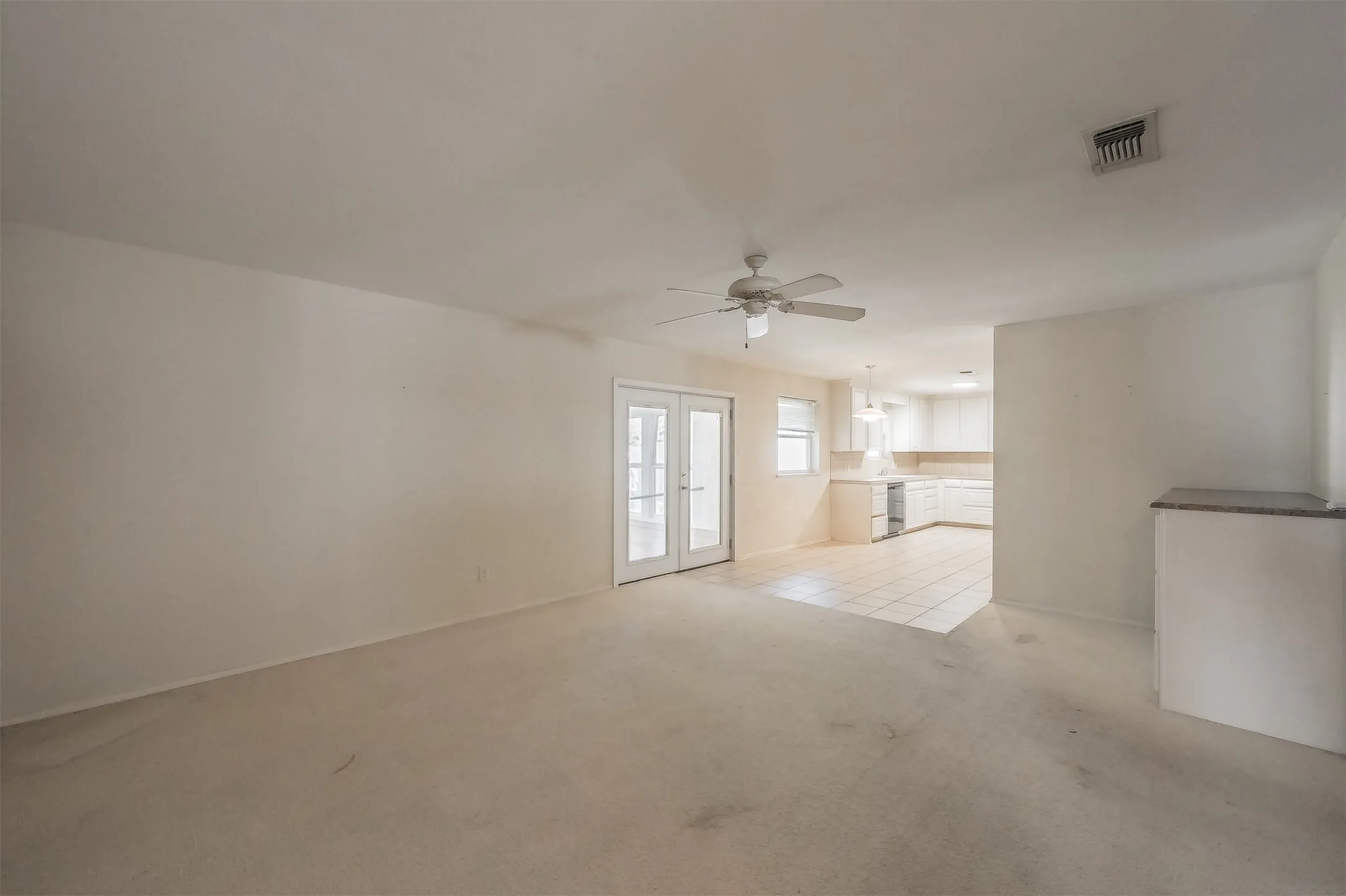 Dual glass panel doors, ceiling fan, tile flooring in kitchen, built-in shelving with stone top, recessed lighting