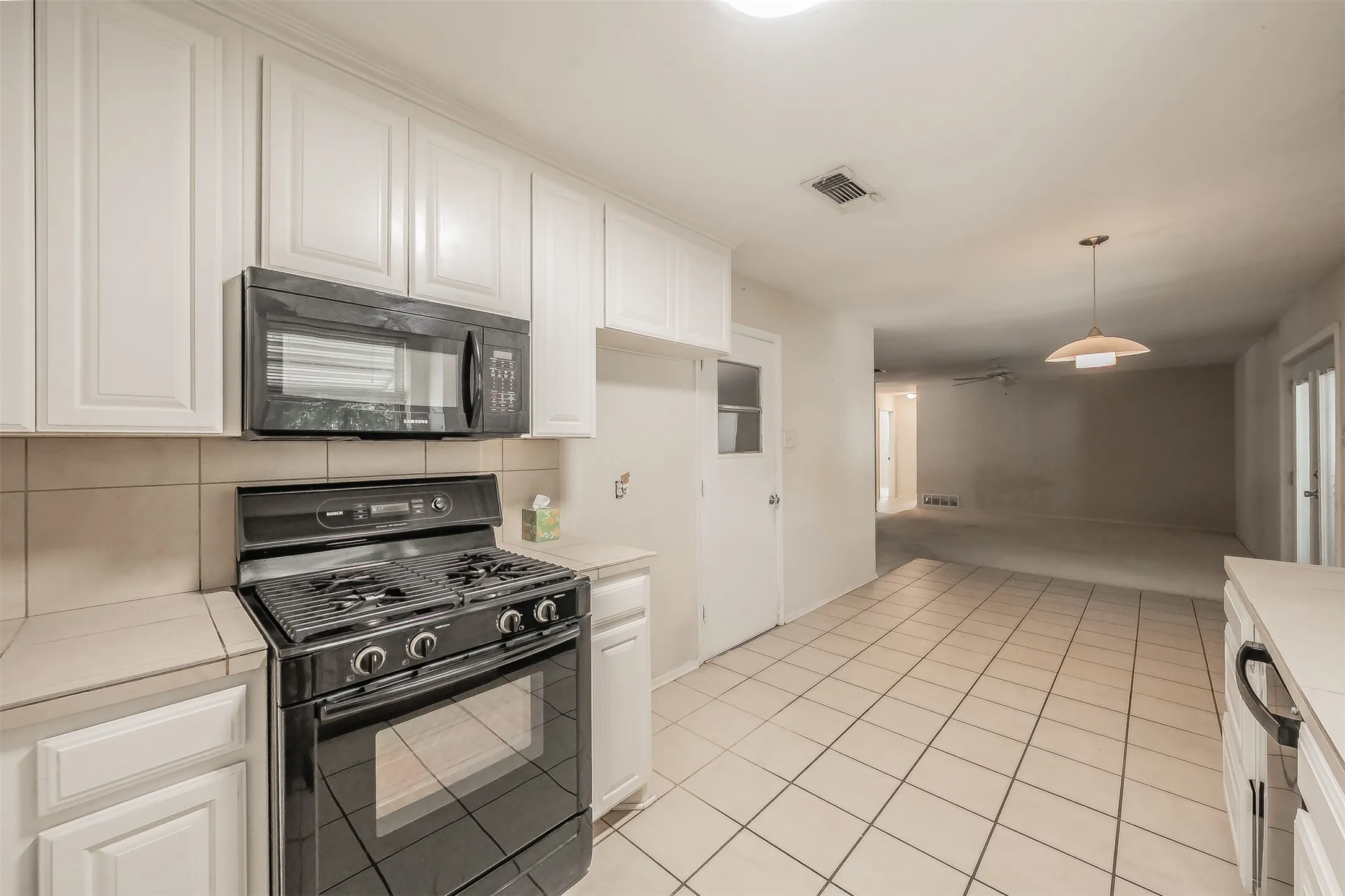 Kitchen featuring white cabinetry, tile flooring, black gas range, and a built-in microwave