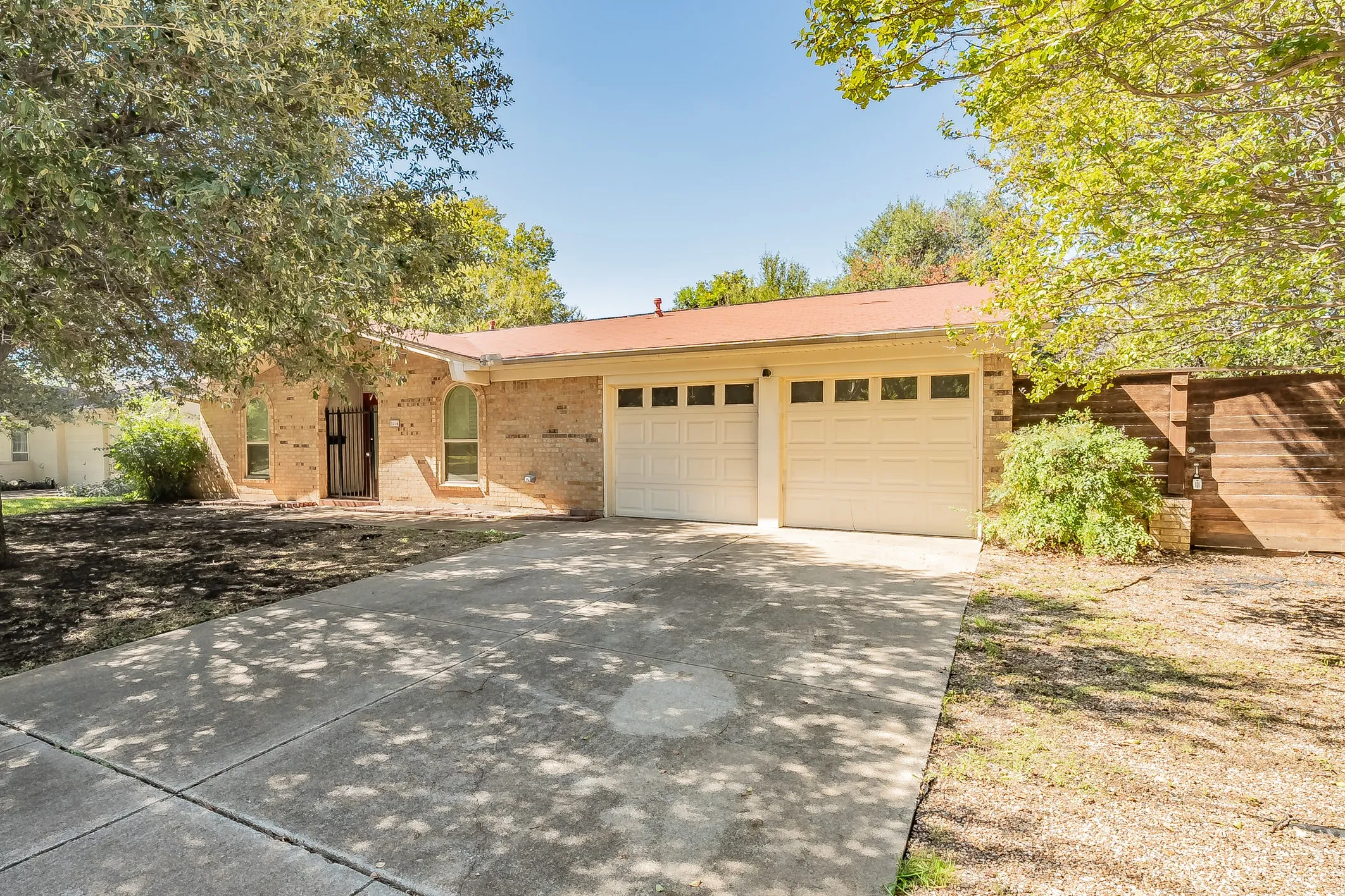 Brick exterior with a two-car garage, concrete driveway, and arched windows