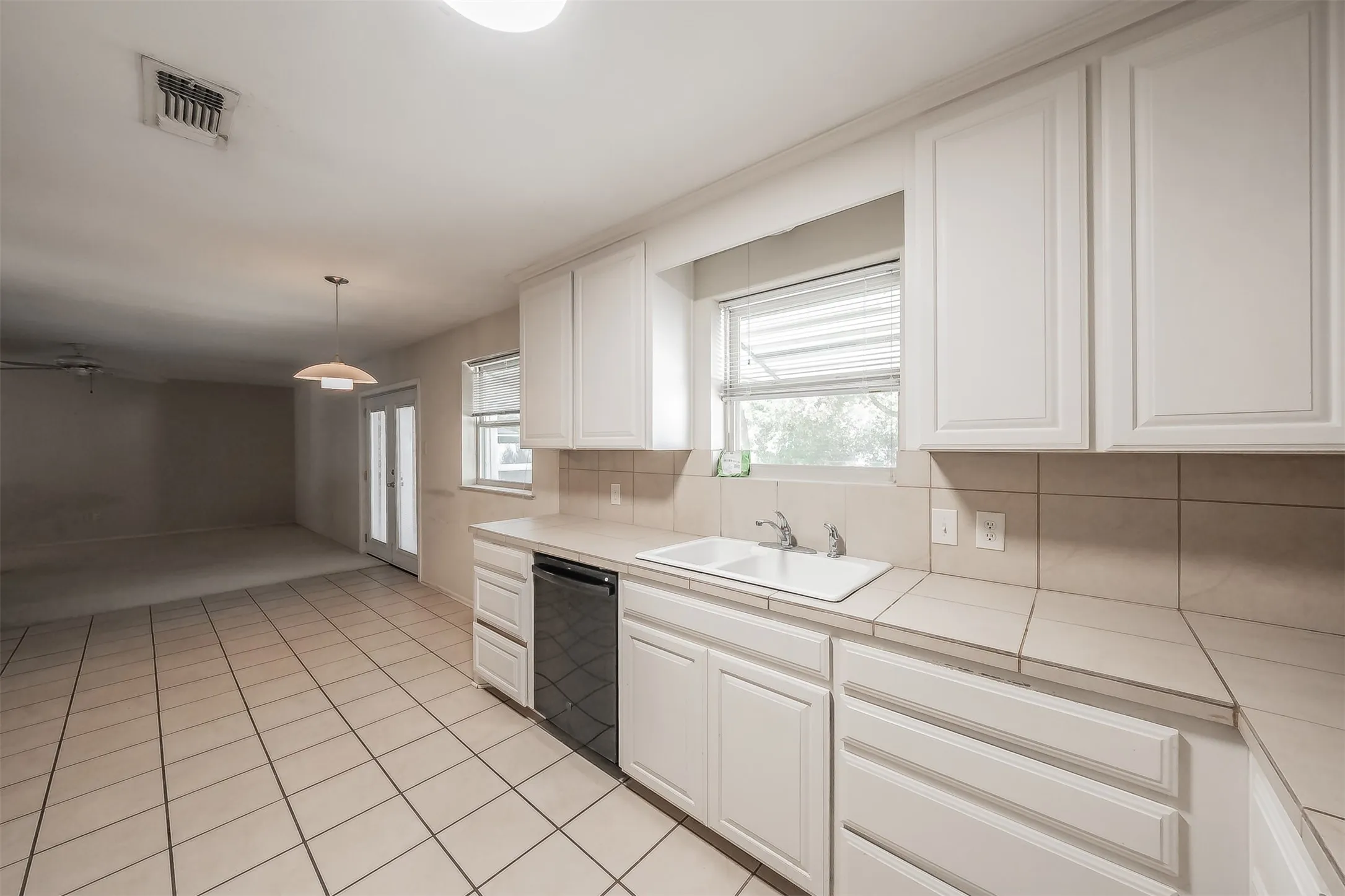 White cabinetry with brushed nickel pulls, ceramic tile flooring, built-in dishwasher, and a double basin sink