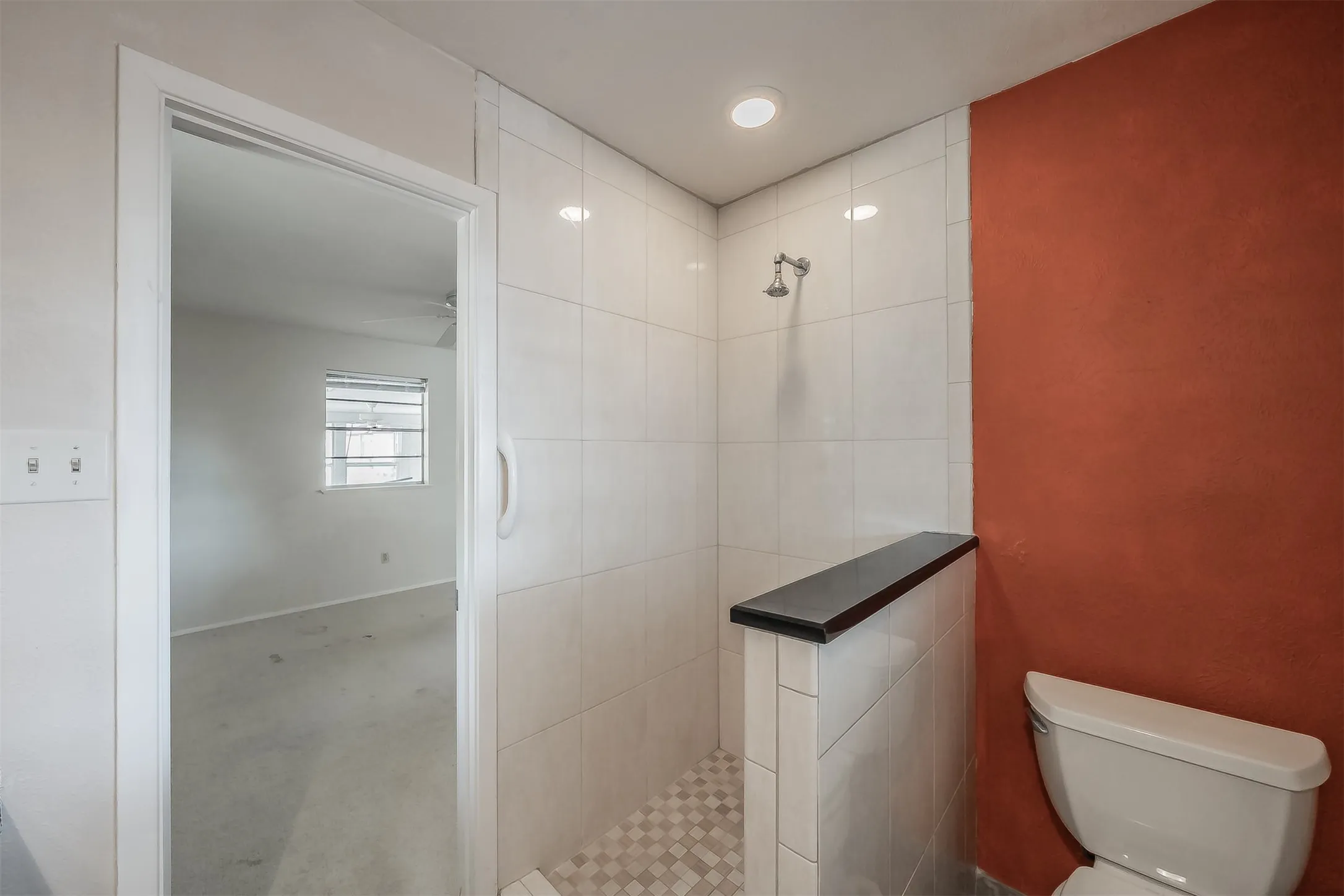 Walk-in shower with tiled walls and floor, featuring a built-in bench