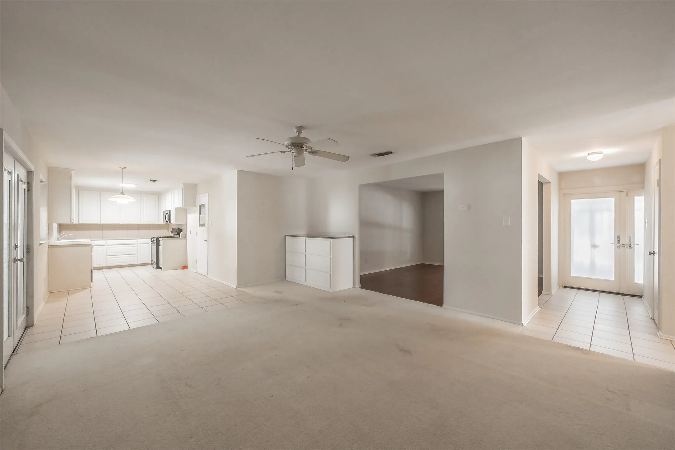 Open-concept living space with carpet flooring and ceiling fan