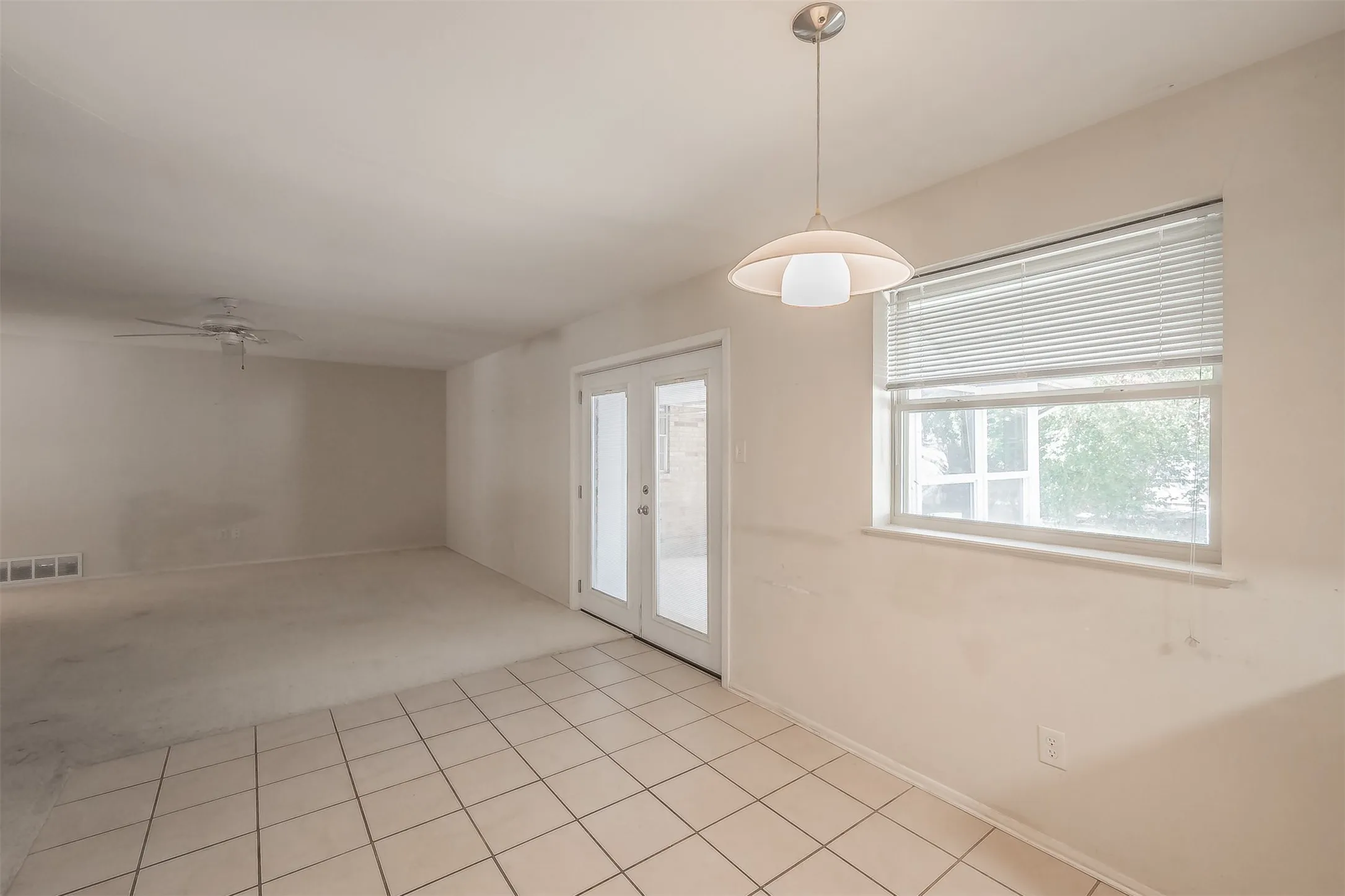 Ceramic tile flooring, white walls, double-pane window, flush-mount ceiling fan, and a contemporary pendant light fixture