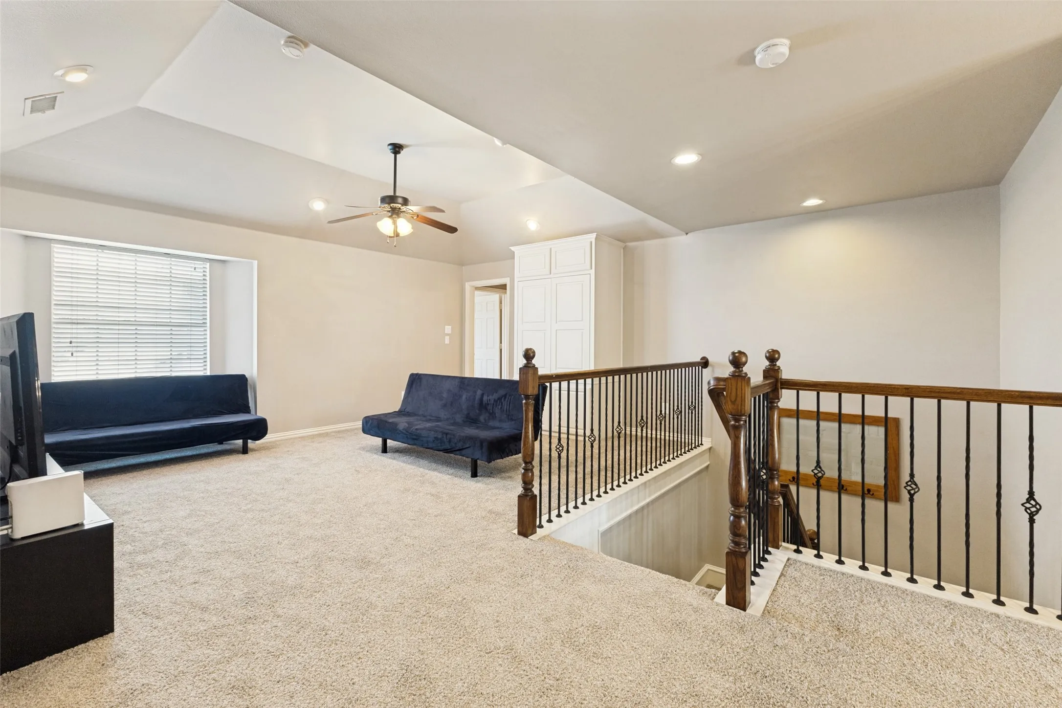 Carpeted upper-level space featuring a vaulted ceiling with recessed lighting and a ceiling fan