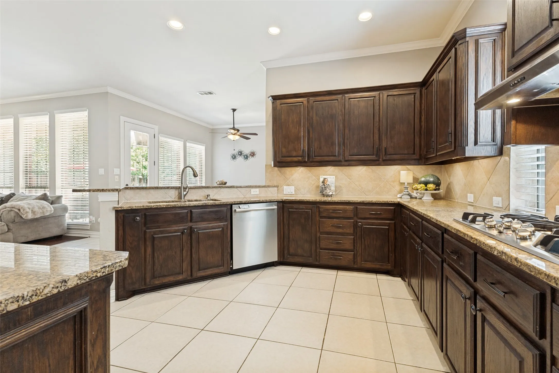 Spacious kitchen featuring dark wood cabinetry, light-toned countertops, and a tile backsplash