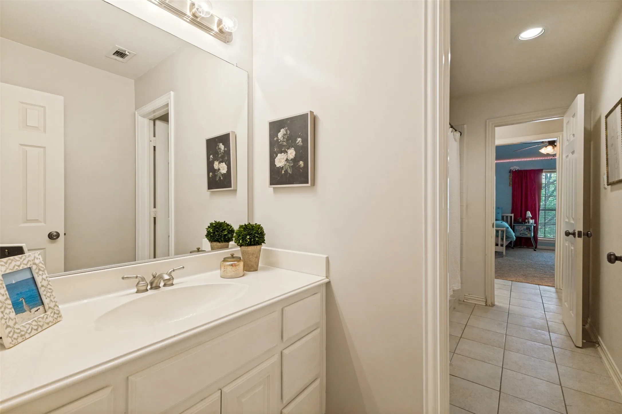 White vanity with integrated sink, chrome faucet, and expansive wall-mounted mirror