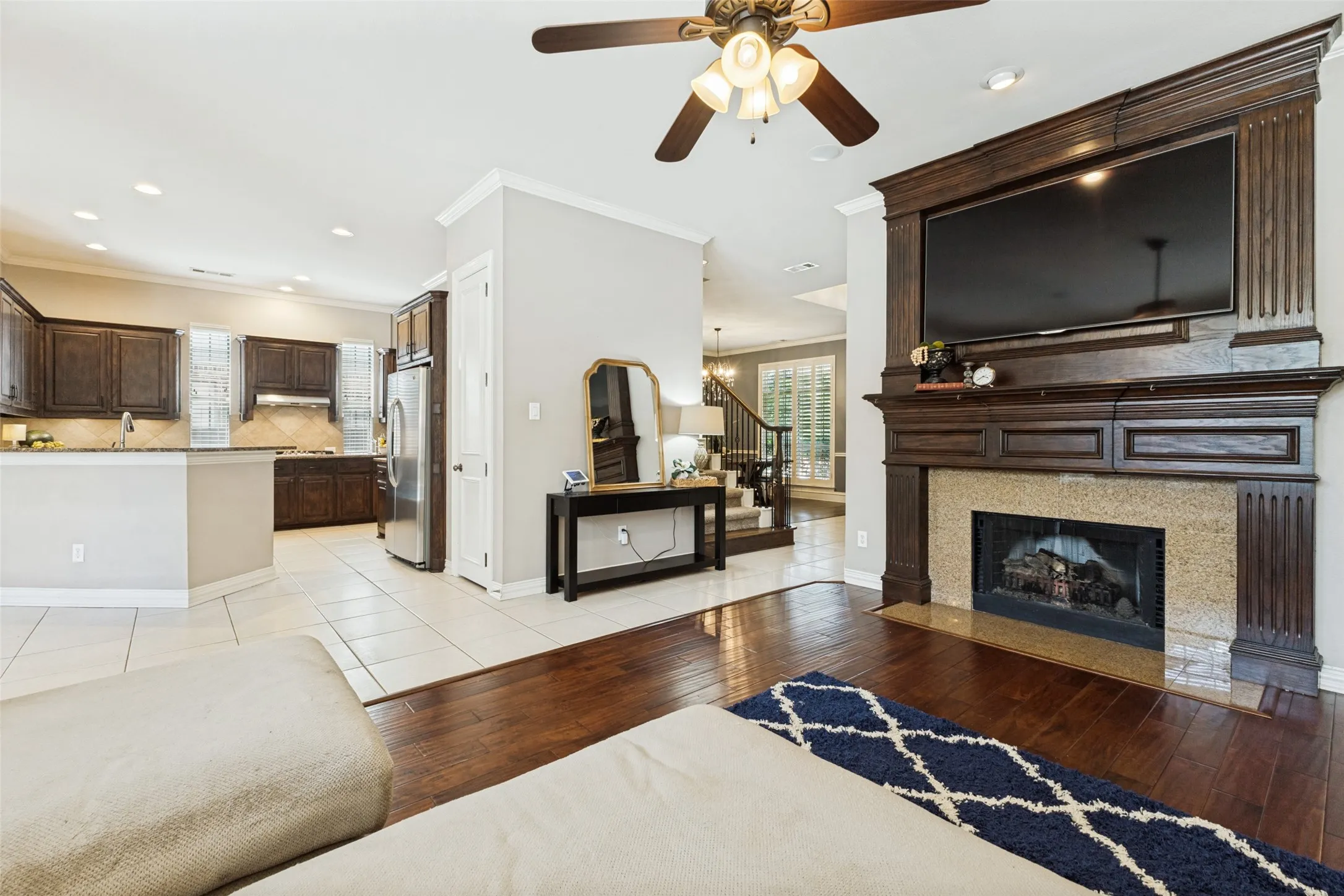 Living area featuring a grand dark wood mantel with an integrated television space and a stone-surround fireplace