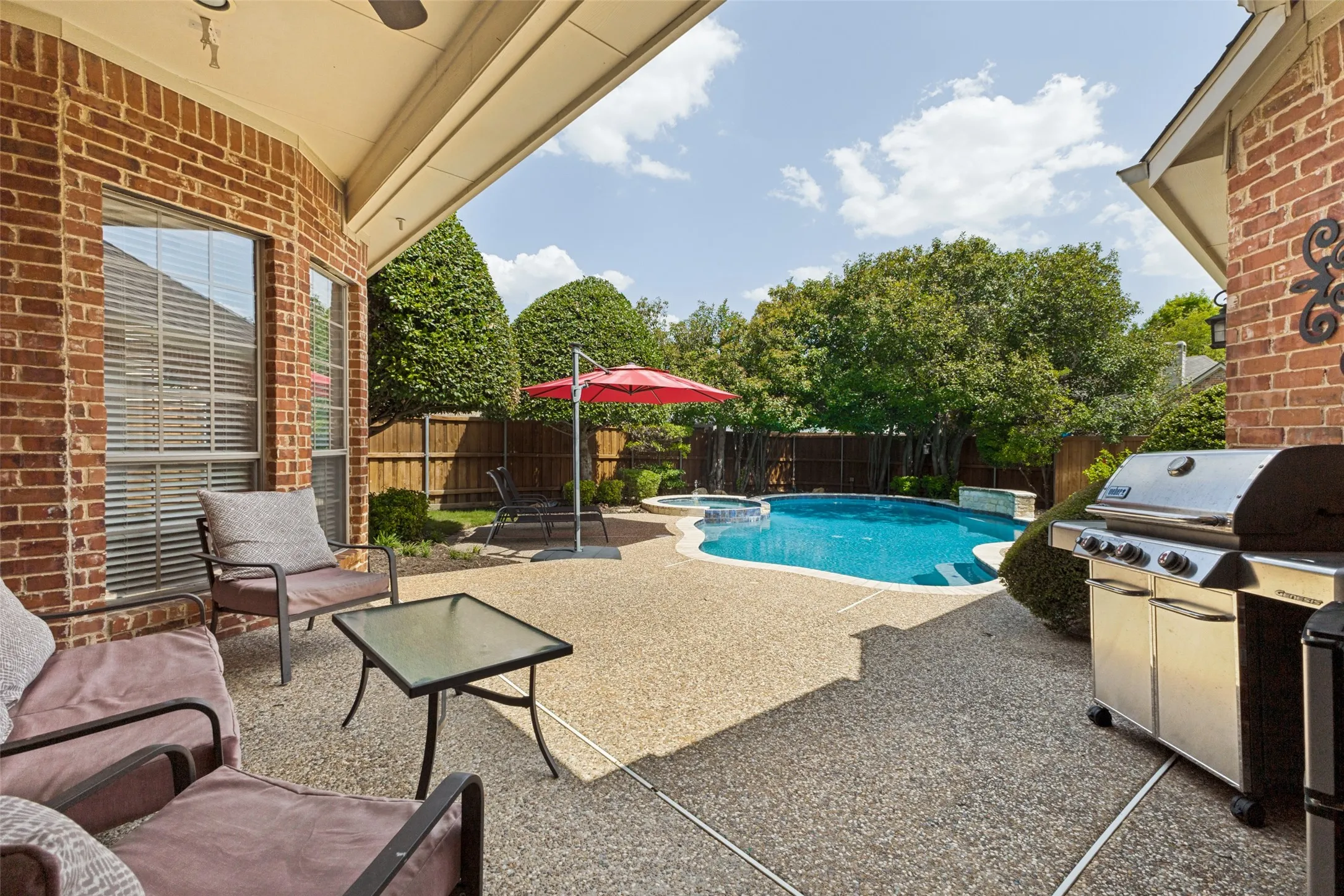 Expansive covered patio featuring an exposed aggregate finish, brick exterior, and a ceiling fan