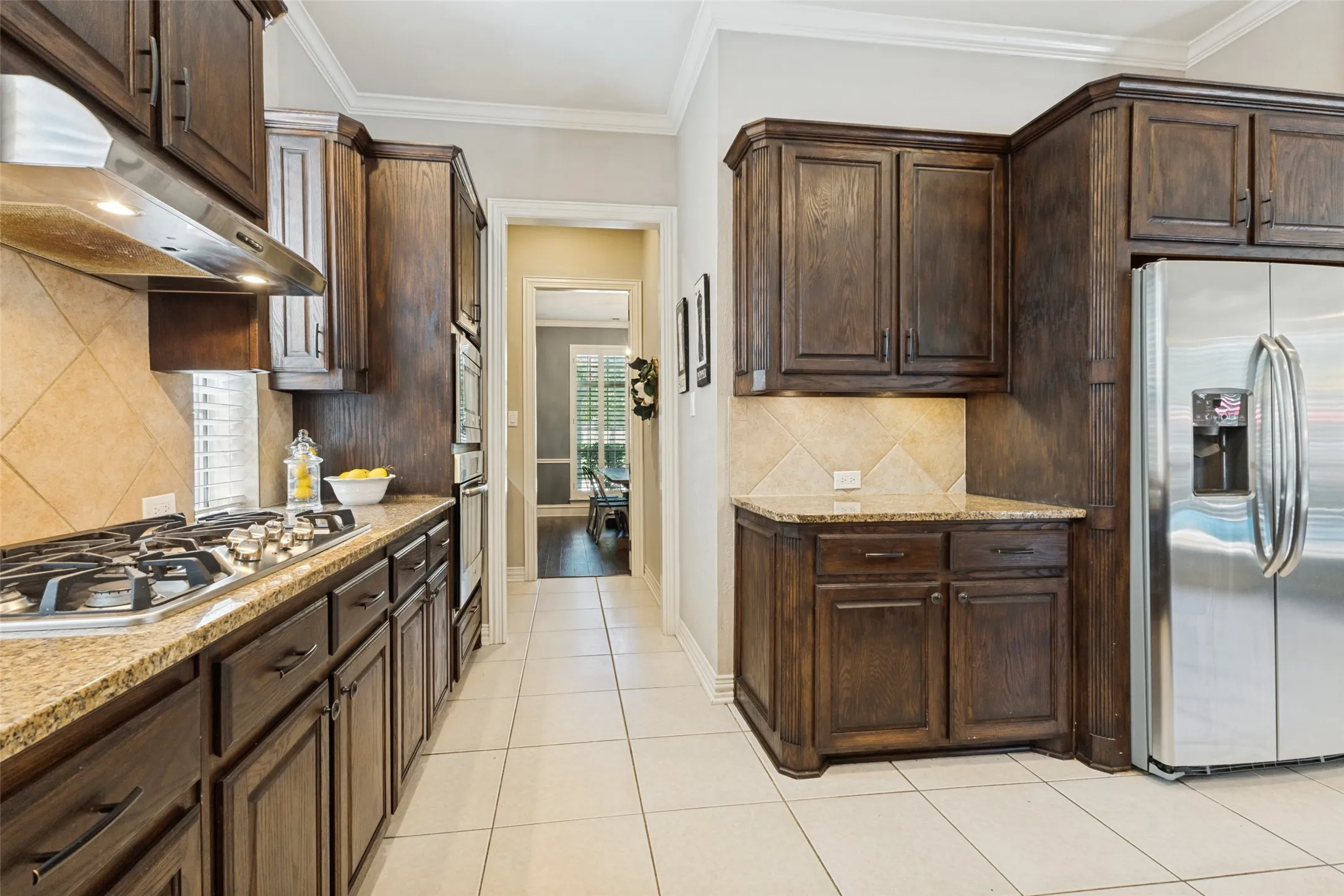 Spacious kitchen featuring dark wood cabinetry, granite countertops, stainless steel appliances, and tile flooring