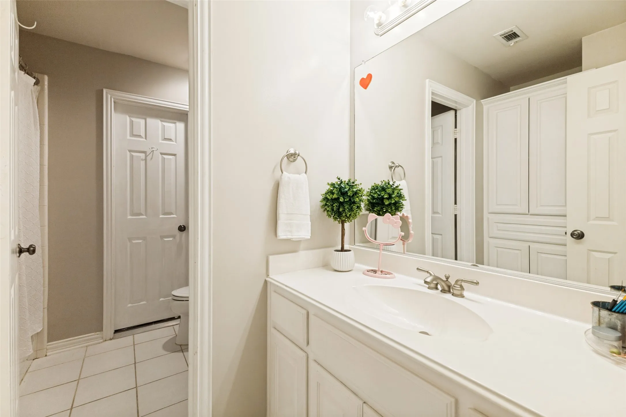 Bathroom vanity featuring a white countertop with integrated sink, brushed nickel faucet, and a large wall-mounted mirror