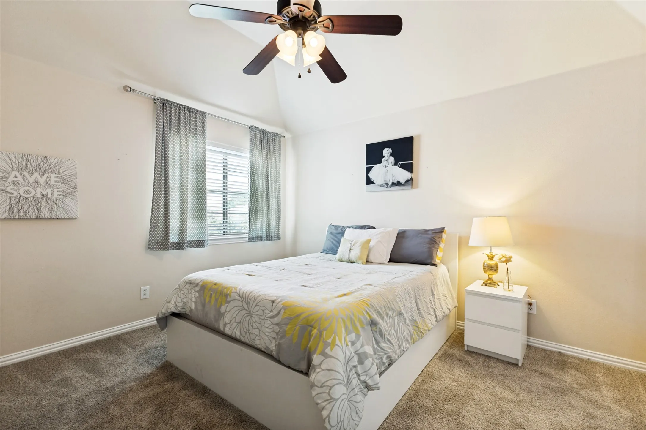 Carpeted room featuring a vaulted ceiling with a ceiling fan, window with blinds, and white baseboards