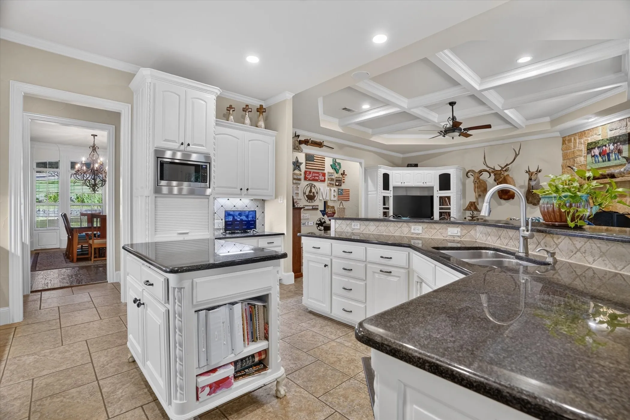 Kitchen featuring ivory cabinetry, dark granite countertops, stainless steel appliances, and an island.