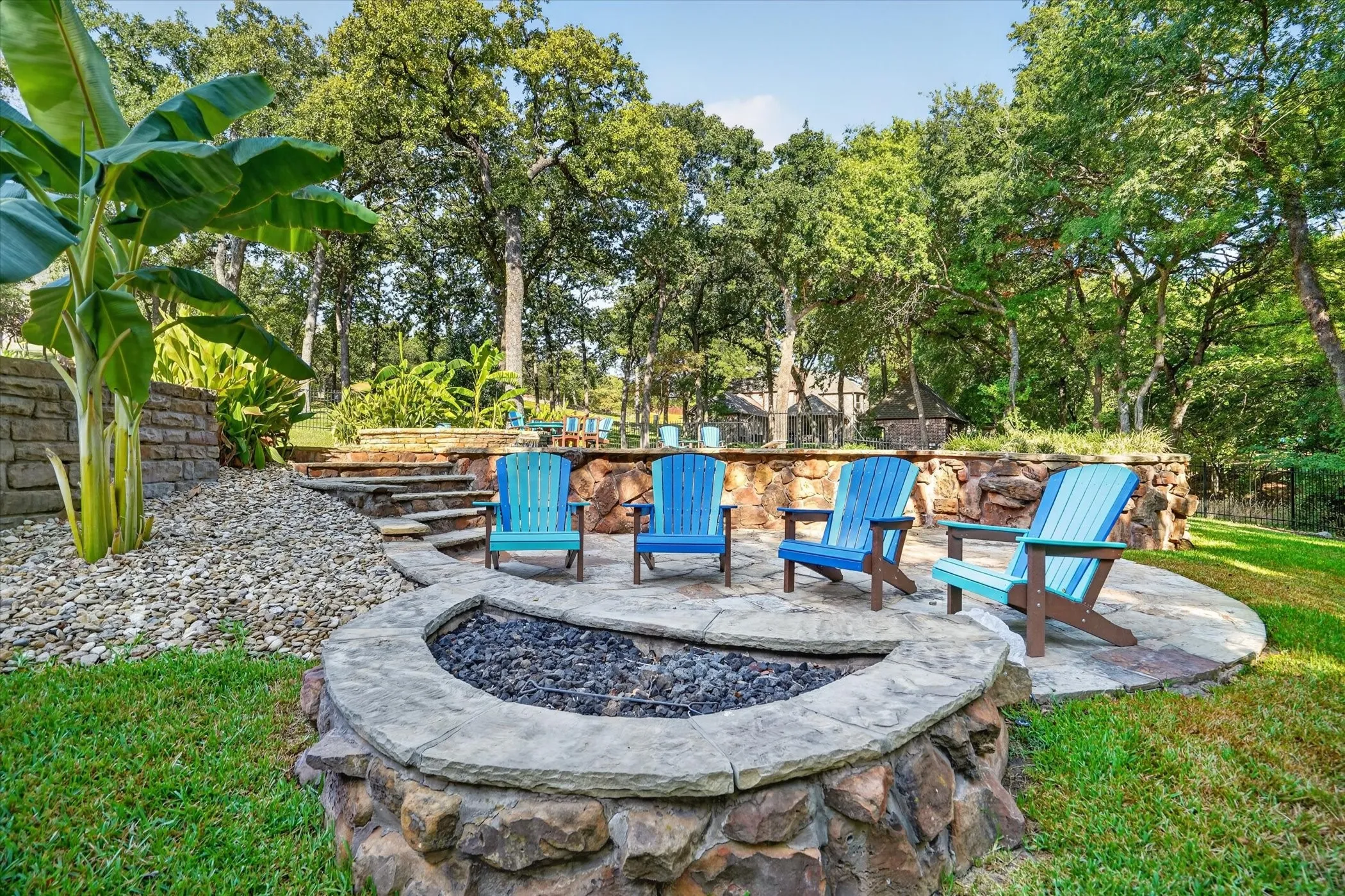 Stone fire pit with surrounding flagstone patio and terraced landscaping