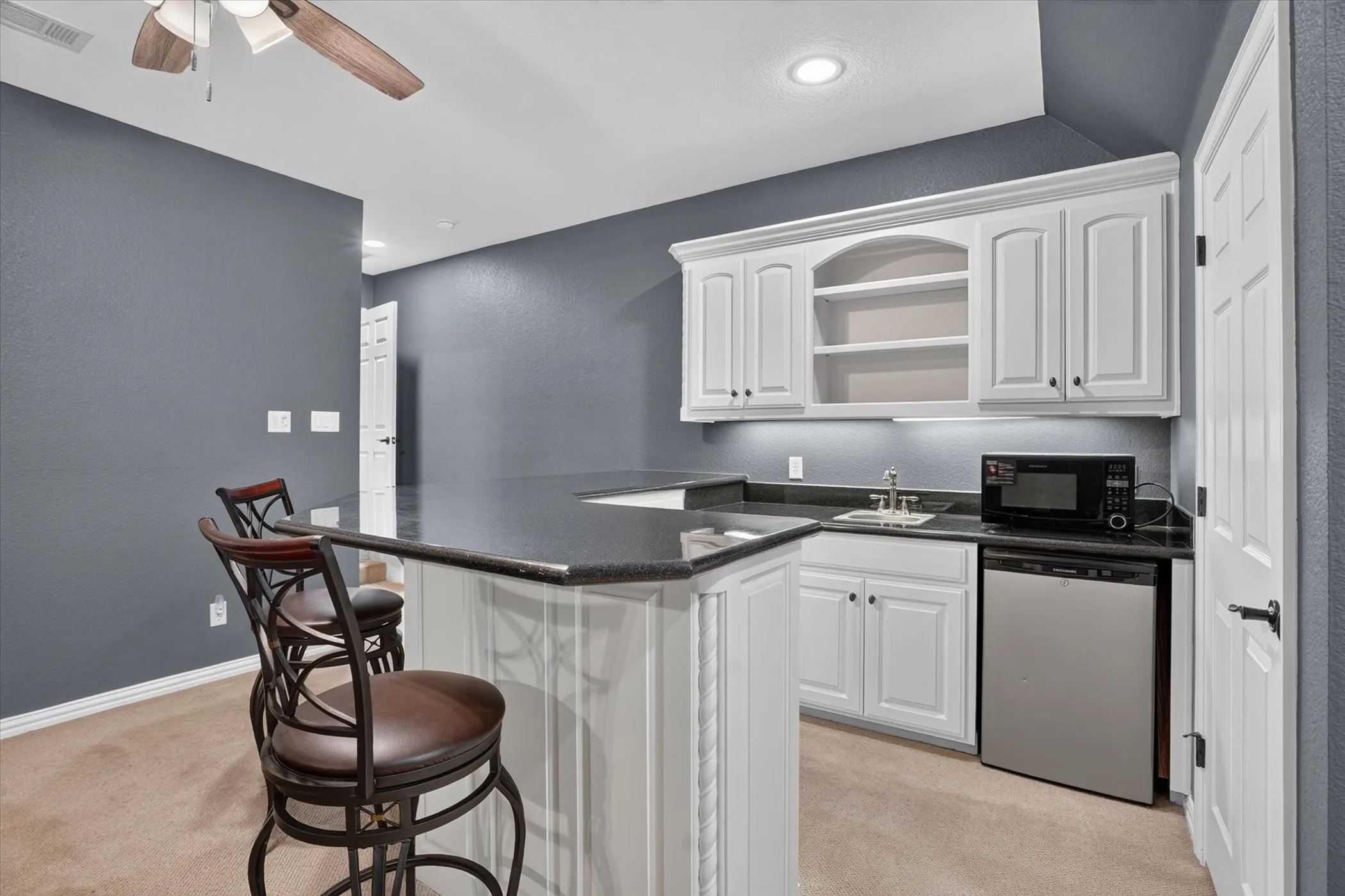 Built-in wet bar with dishwasher, dark countertops, and under-cabinet lighting