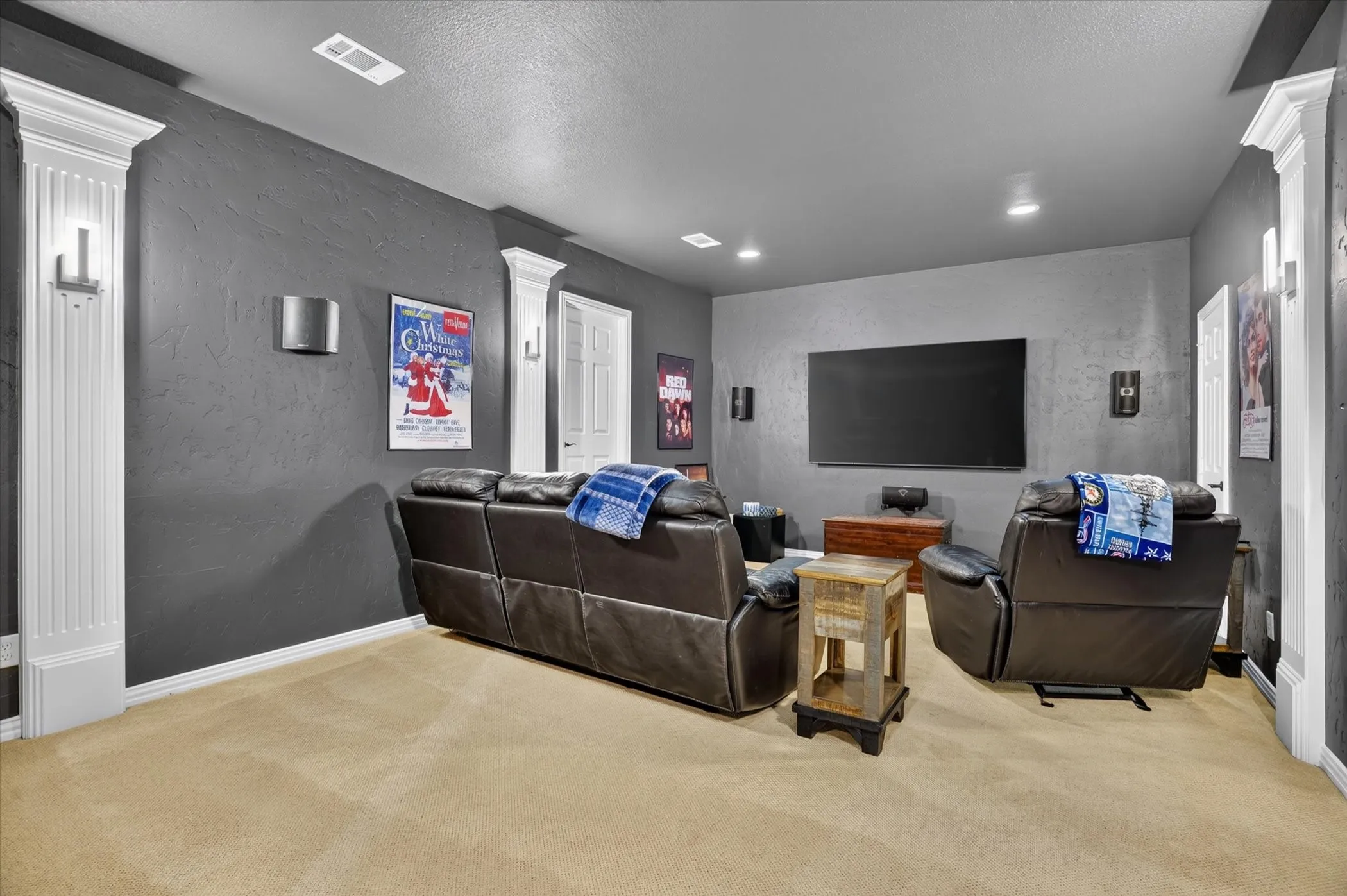 Plush carpet flooring, recessed ceiling lighting, wall-mounted sconces, and white trim accents