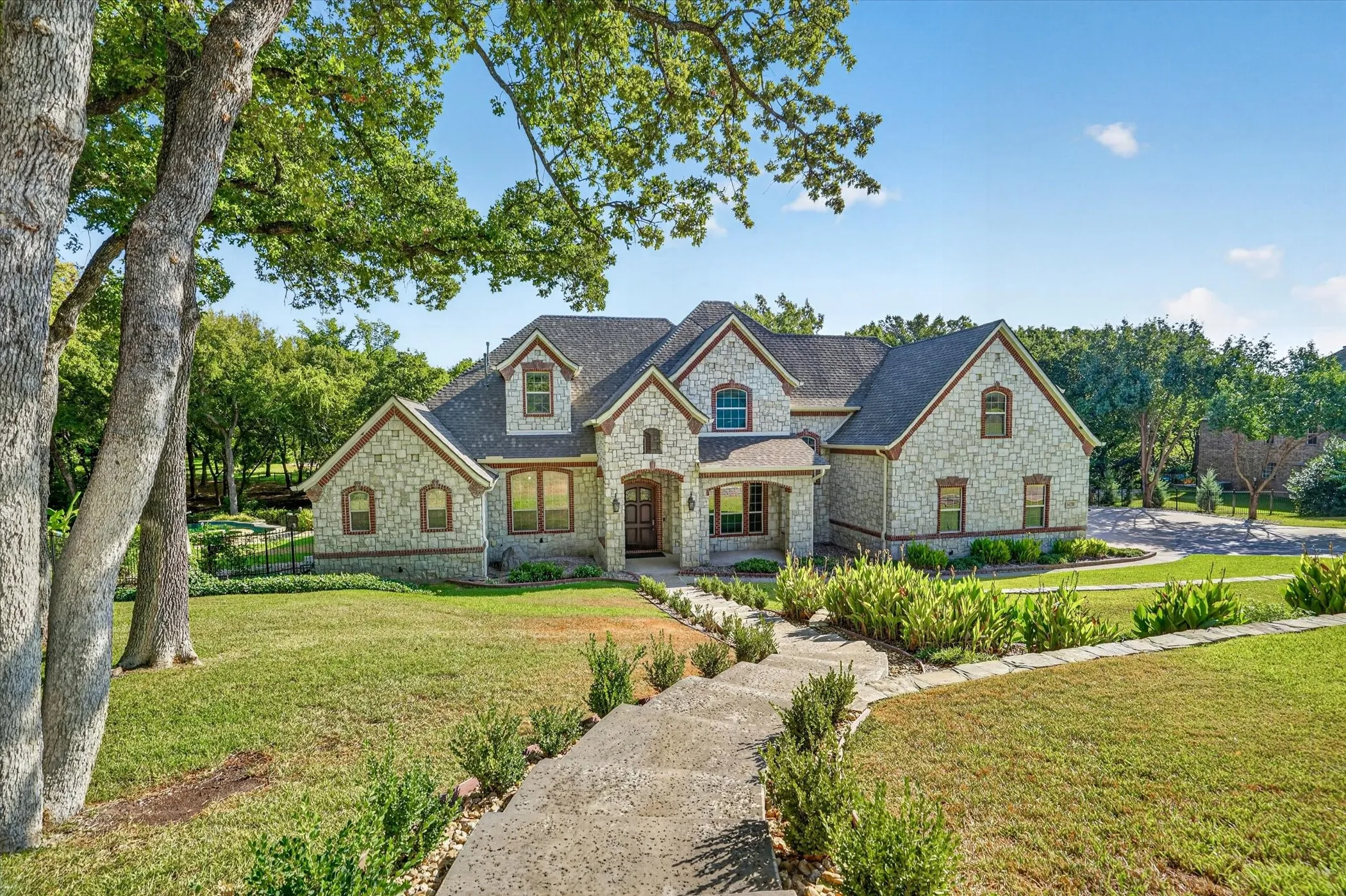 Stone exterior with dormer windows, a covered entry, gabled rooflines, and a stone walkway