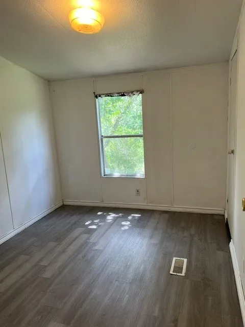Wood-finish flooring with a window and a ceiling-mounted light fixture