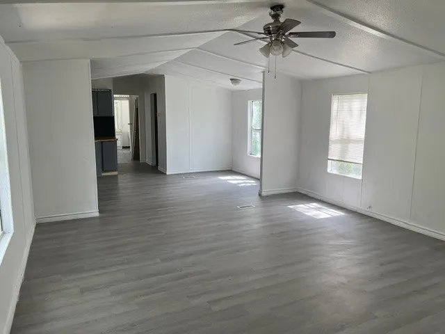 Open-concept living space featuring wood-finish flooring, white walls, and a ceiling fan