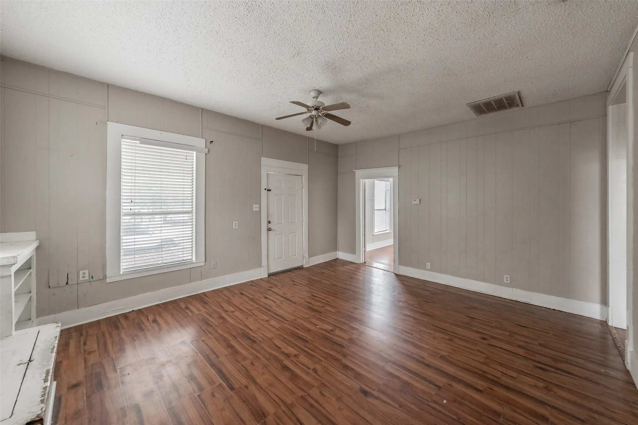 Wood-finish flooring throughout, ceiling fan, and white trim