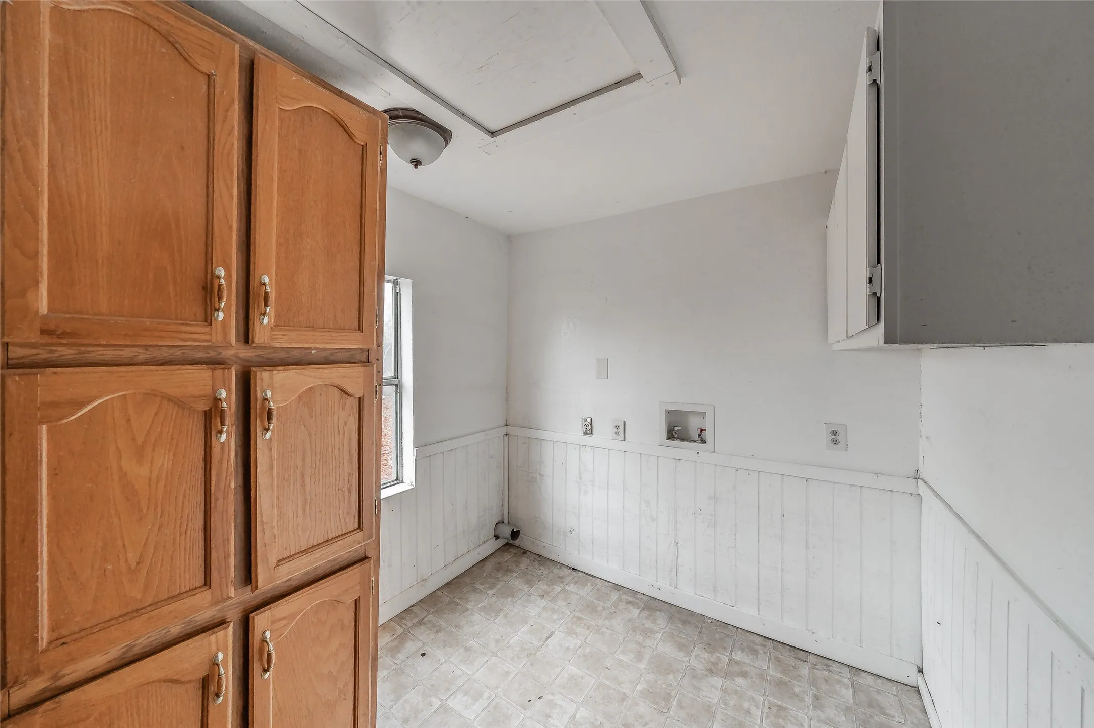 Wood-finish cabinetry, built-in storage, and a utility sink hookup