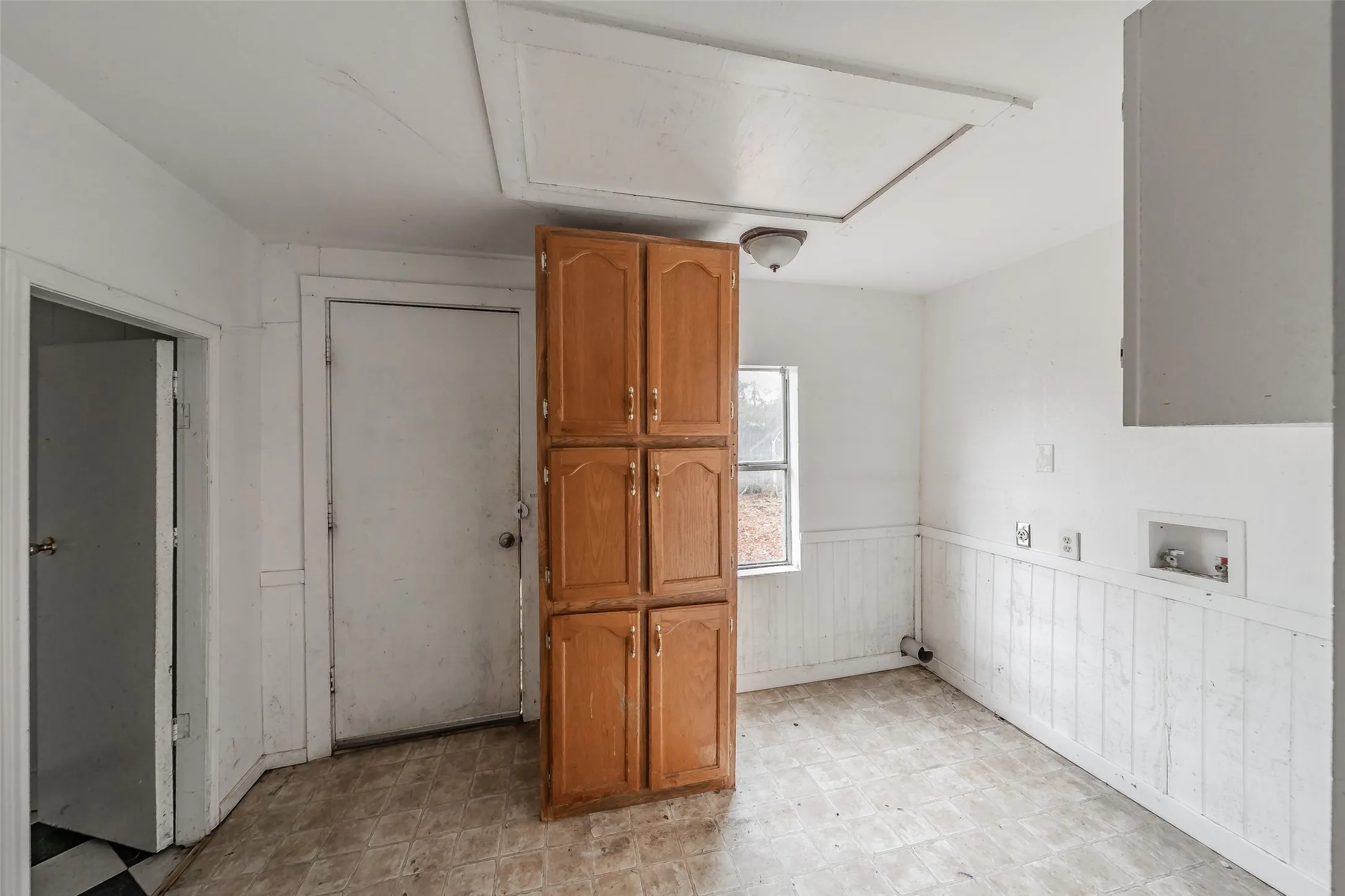Wood-finish cabinetry, beadboard wainscoting, and a single window